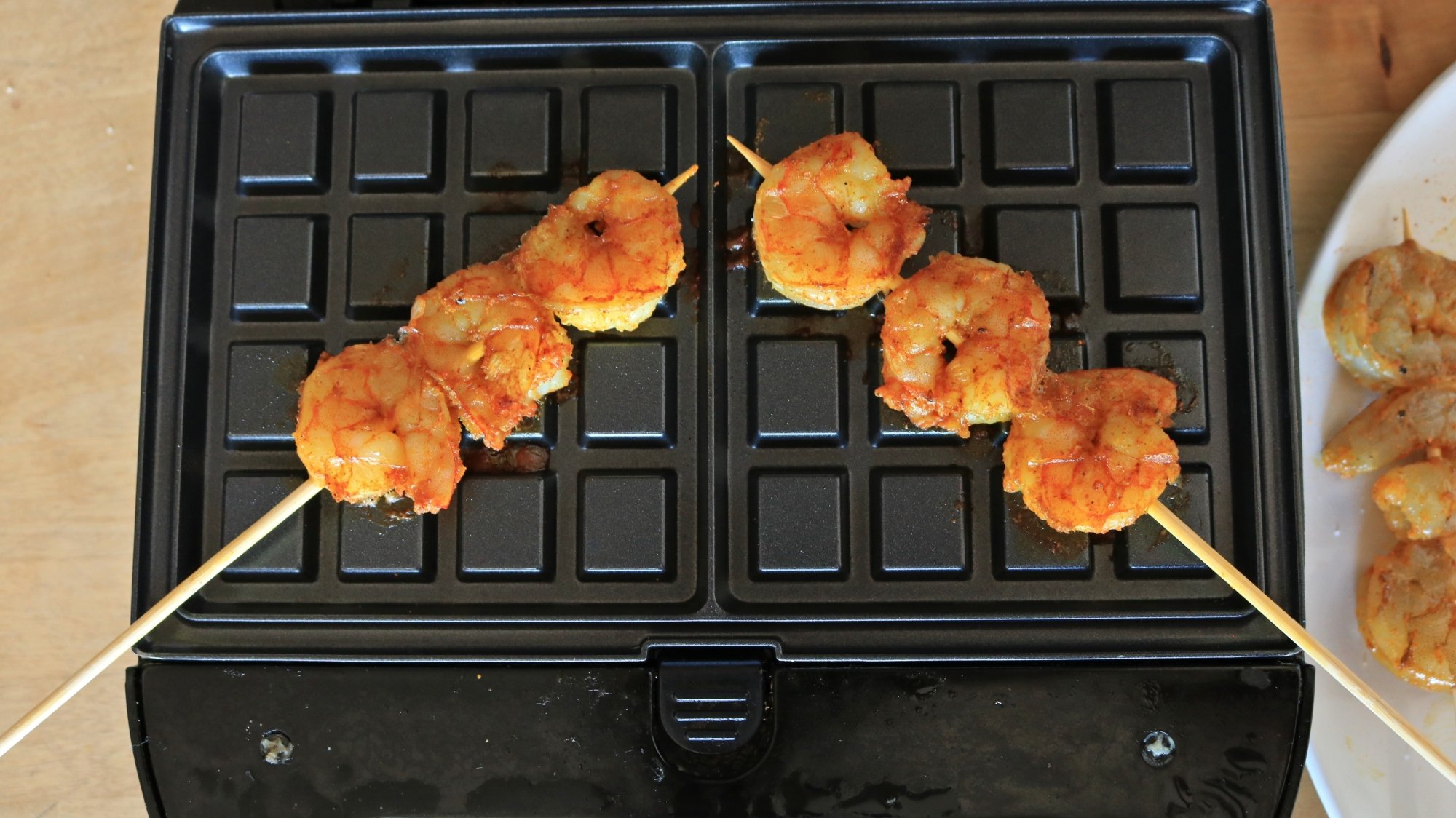 Skwered shrimp on a waffle iron.