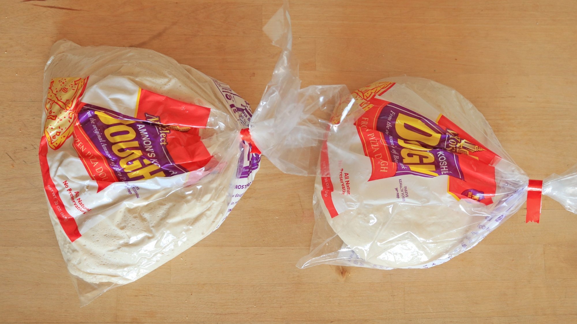 Two balls of raw pizza dough in plastic bag packaging.