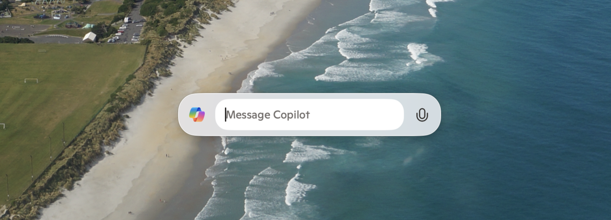 A cute little pop-up window that says "Message Copilot". The wallpaper is a Dunedin  beach photographed from above in March 2020.