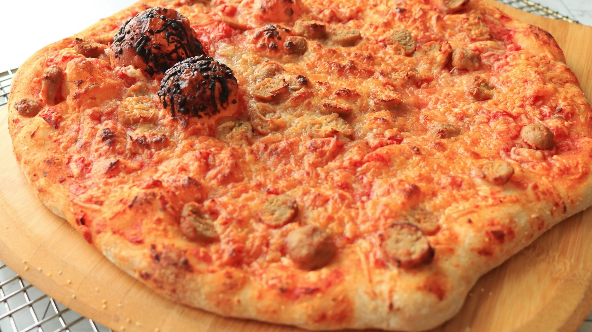 A meatball pizza on a wooden board.