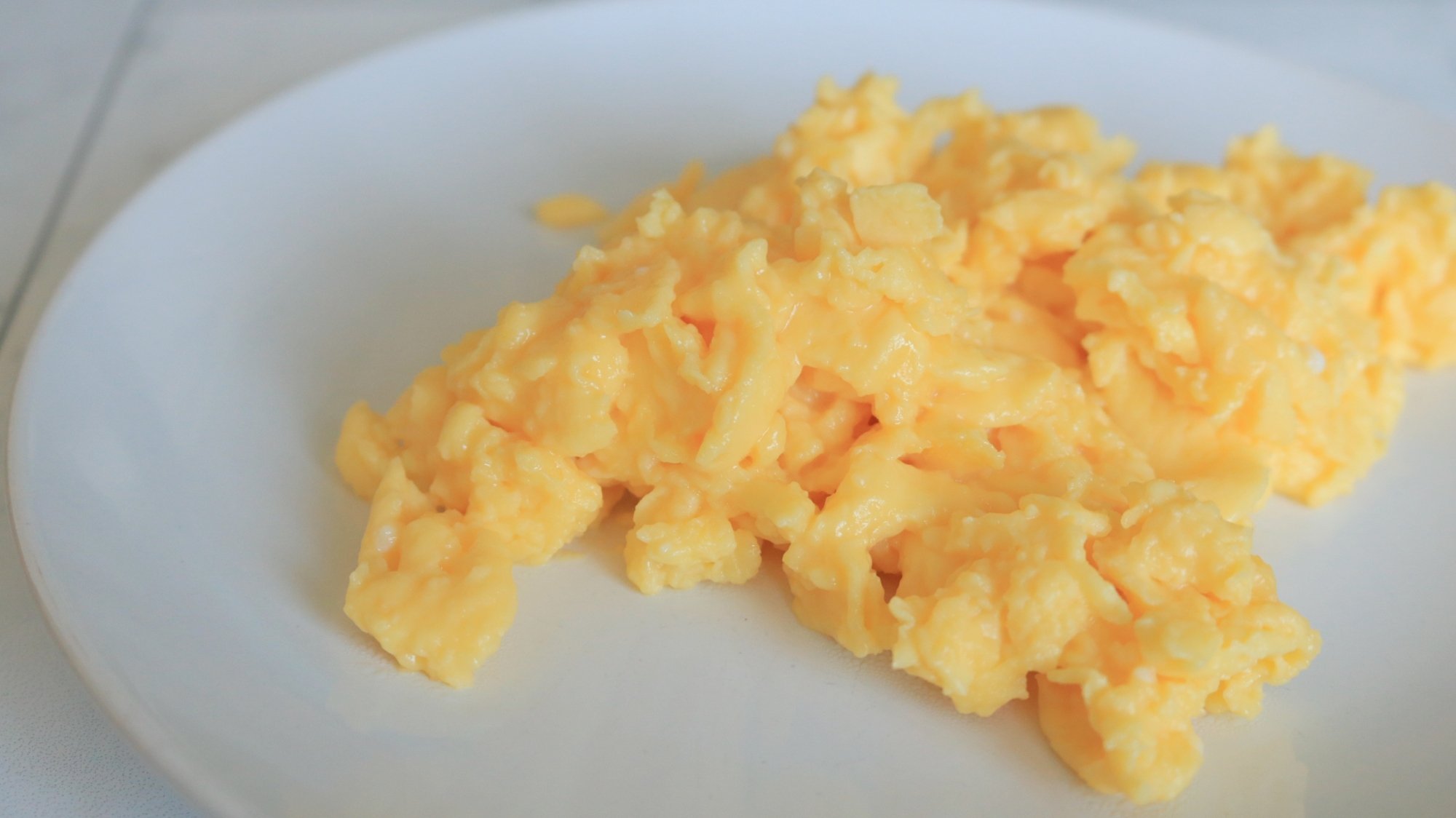 Whisked scrambled eggs on a white plate.
