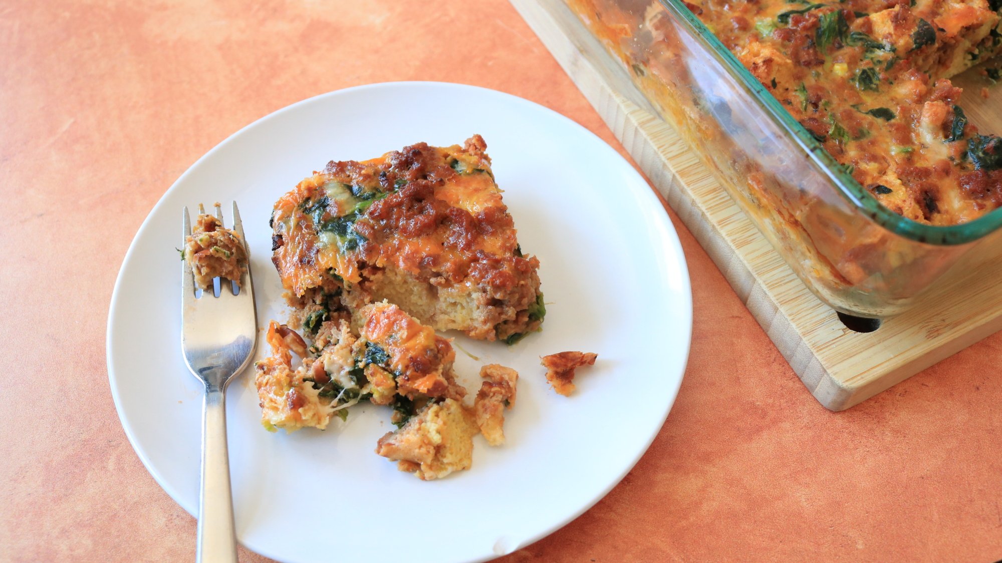 A half-eaten casserole on a plate with a fork.