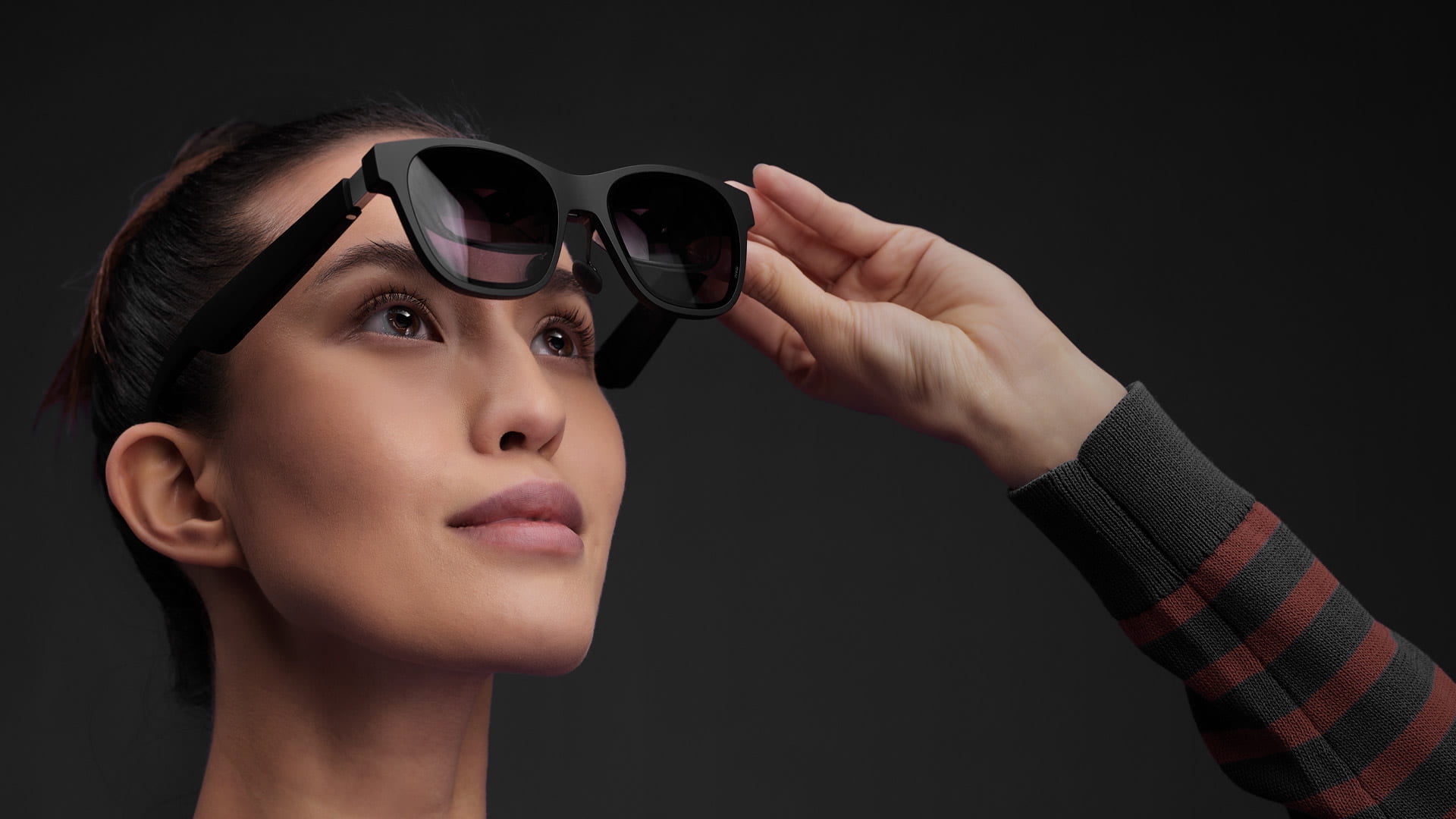A woman lifts Nreal Air off her face and looks through the lenses.