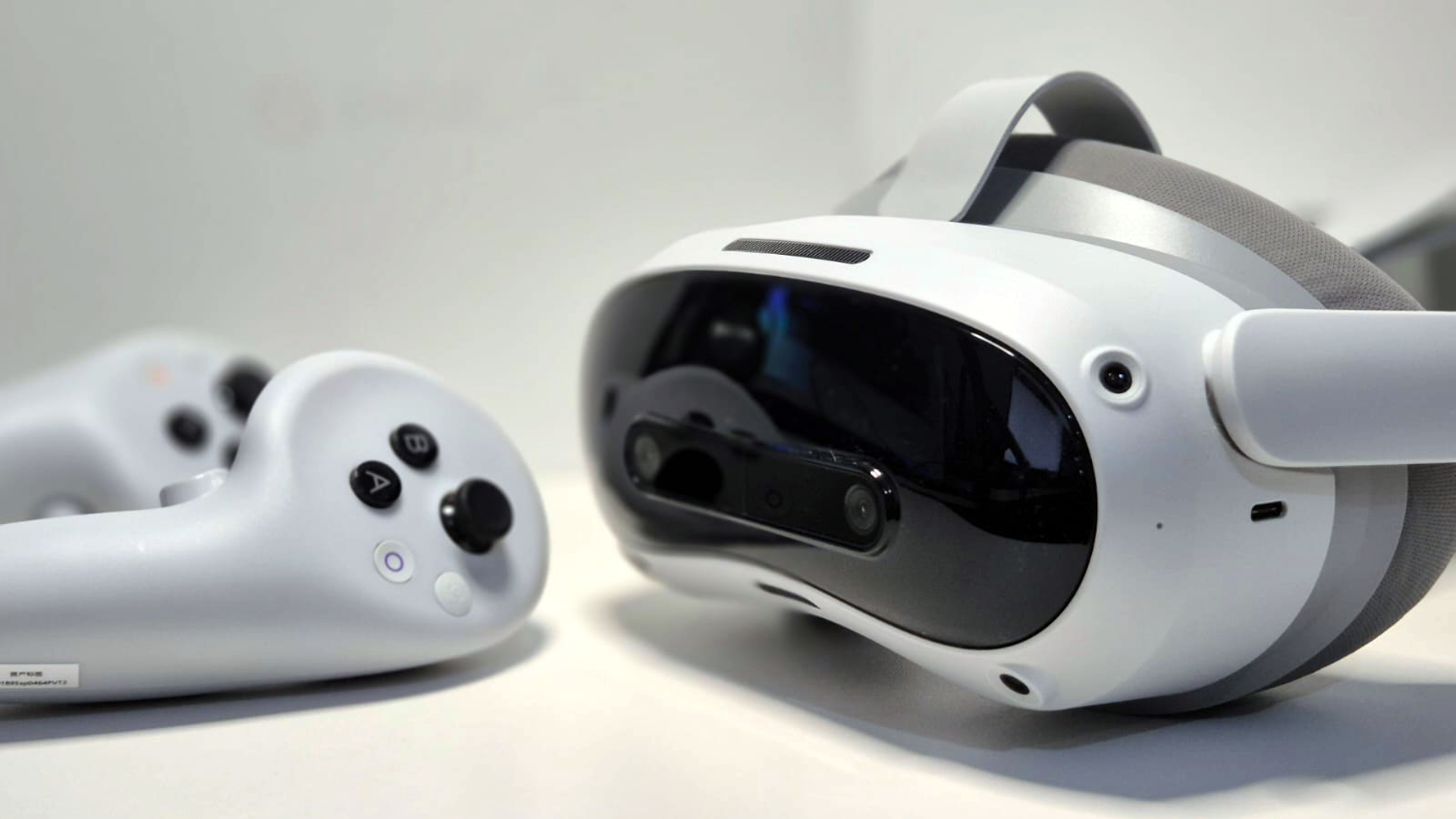 The Pico 4 Ultra VR headset lies on a white table with two VR controllers.