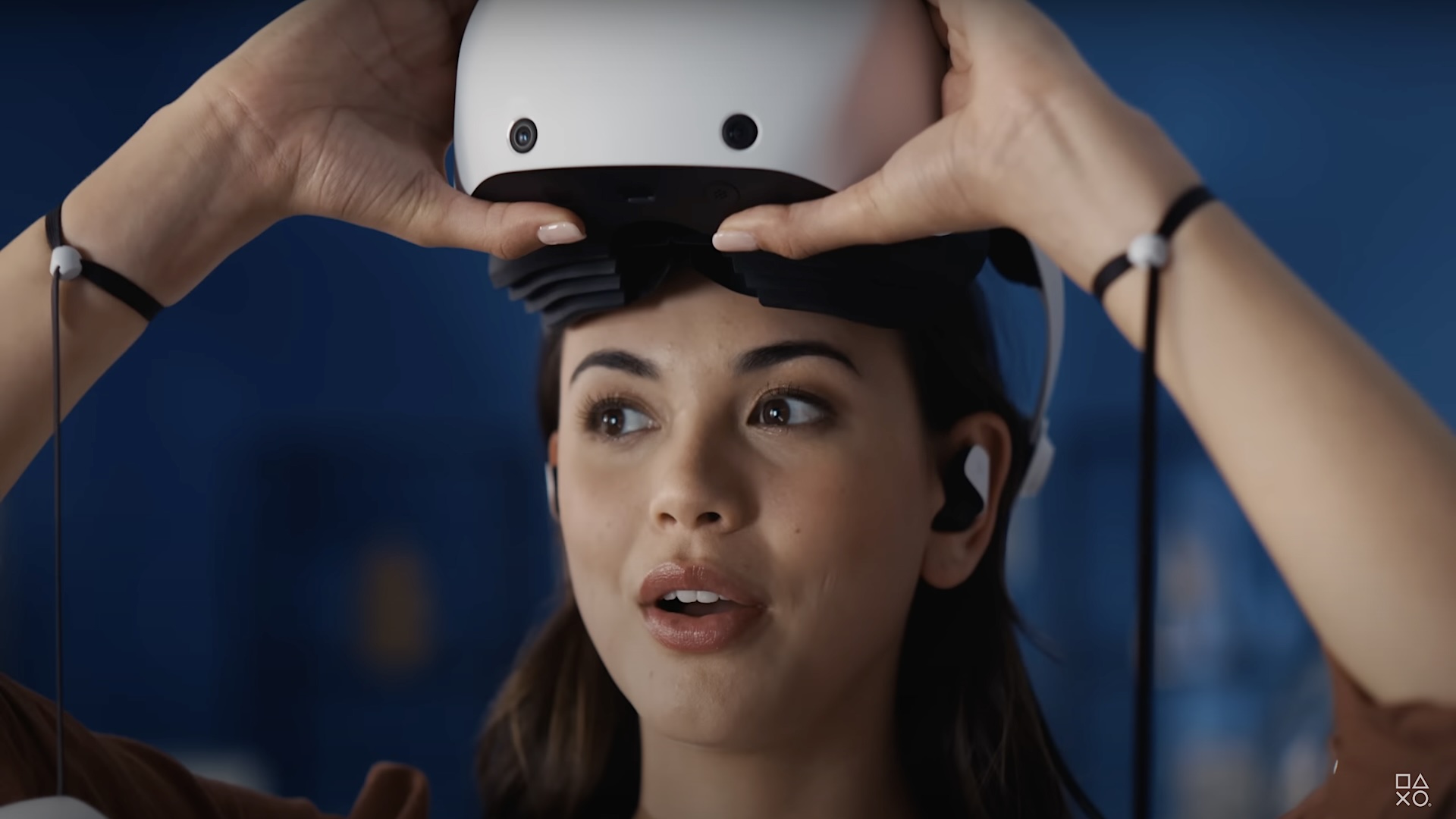 A woman lifts the PSVR 2 from her face with an astonished look on her face.