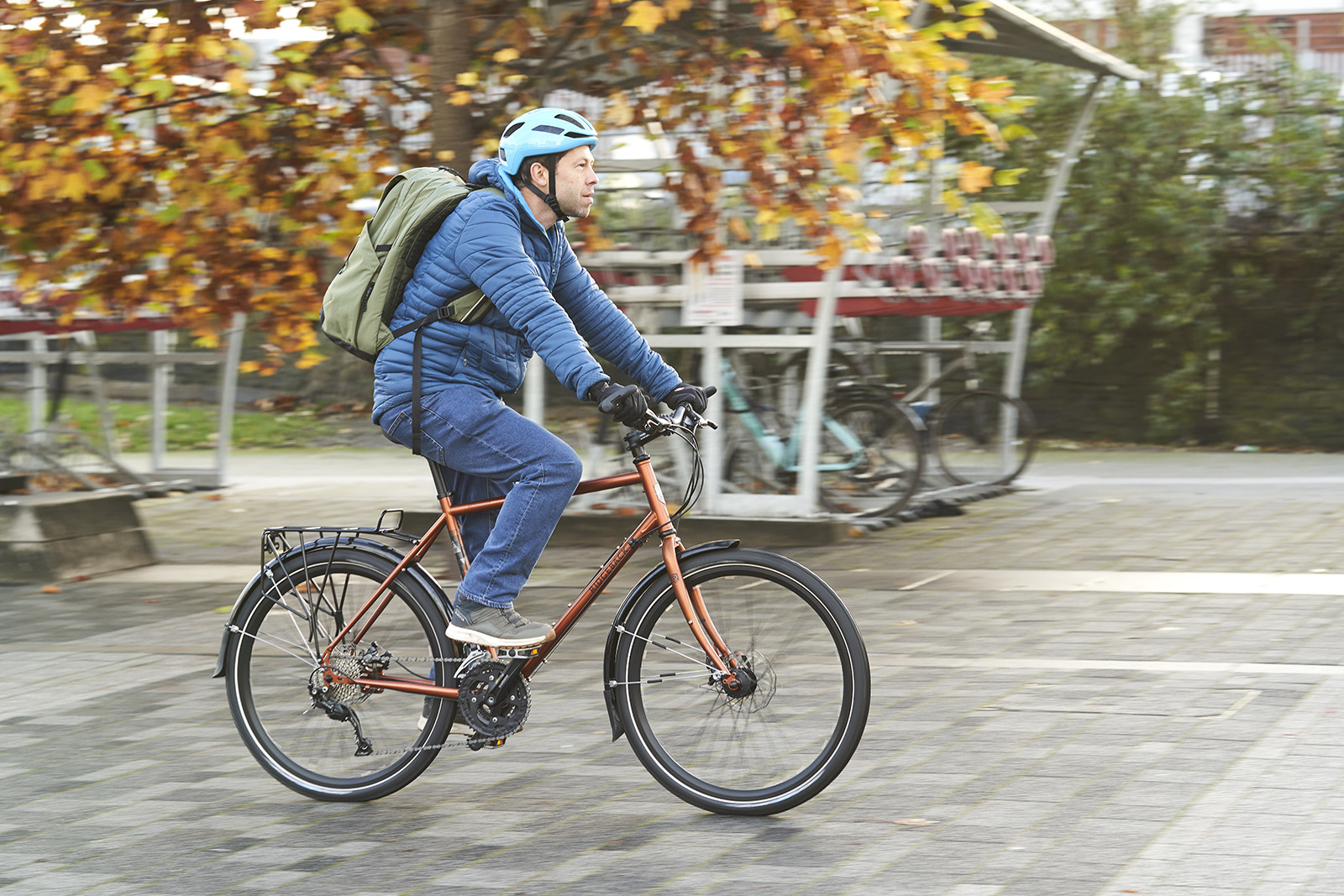 Male cyclist in a blue coat riding the Ridgeback Expedition commuter bike