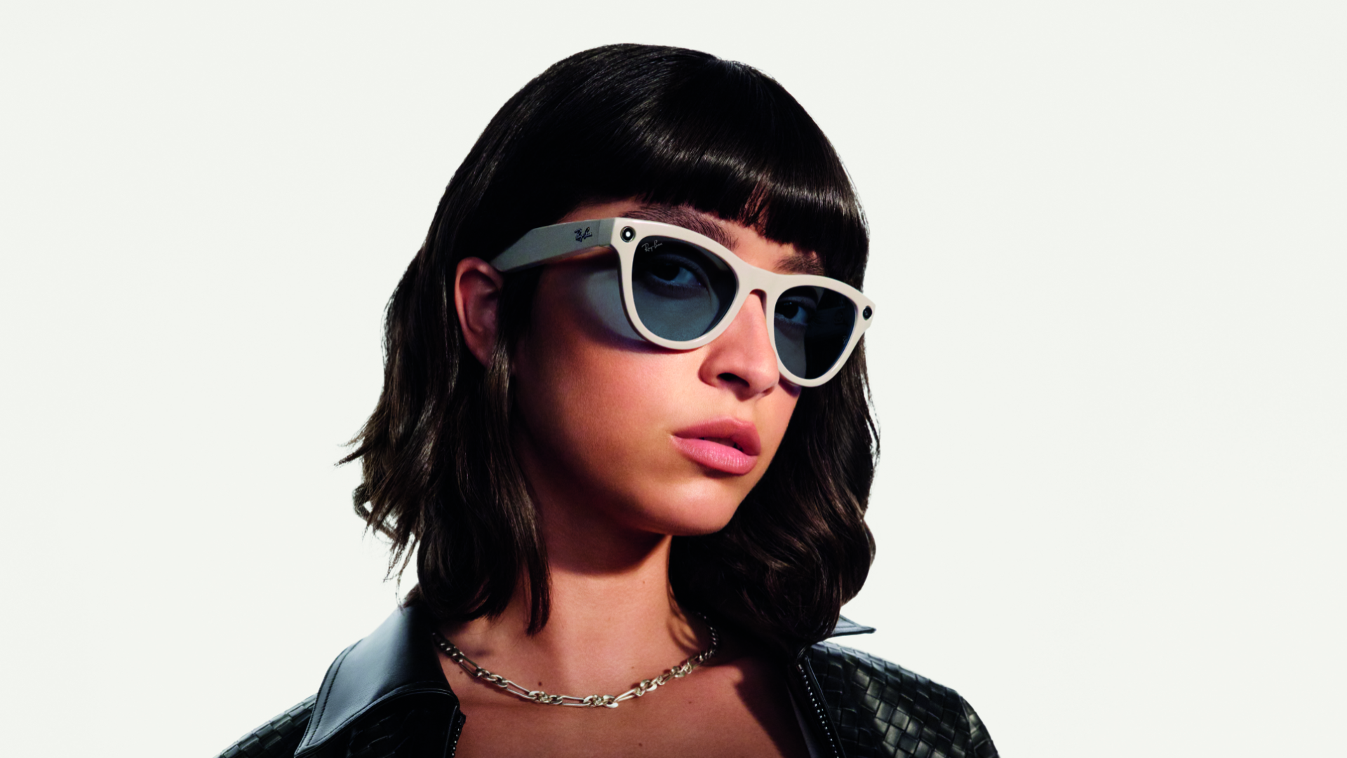 A woman wears white Ray-Ban | Meta Smart Glasses in the Skyler Shiny Chalky Gray style.