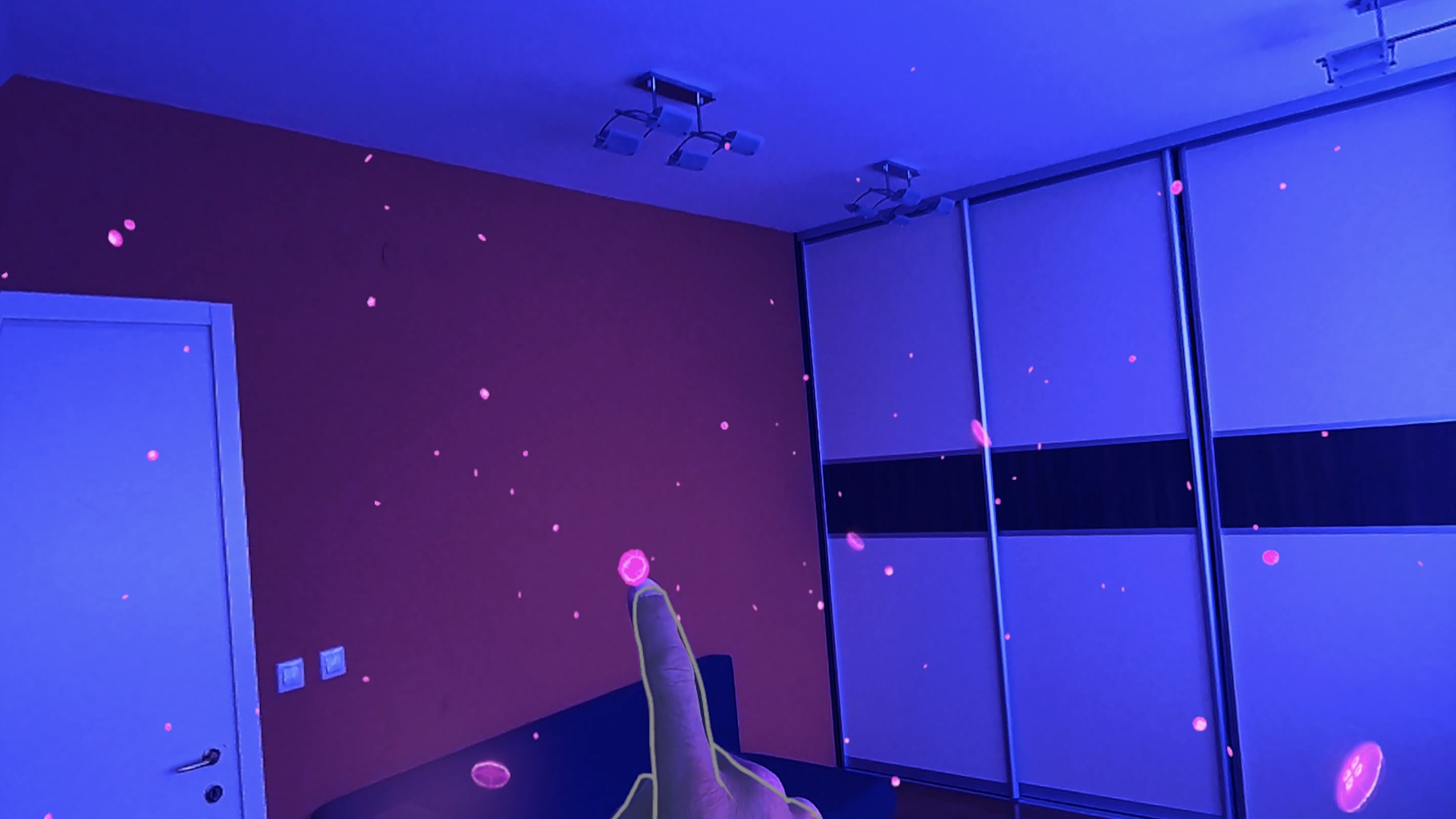 A finger touches a mini MR jellyfish in a blue-colored room.