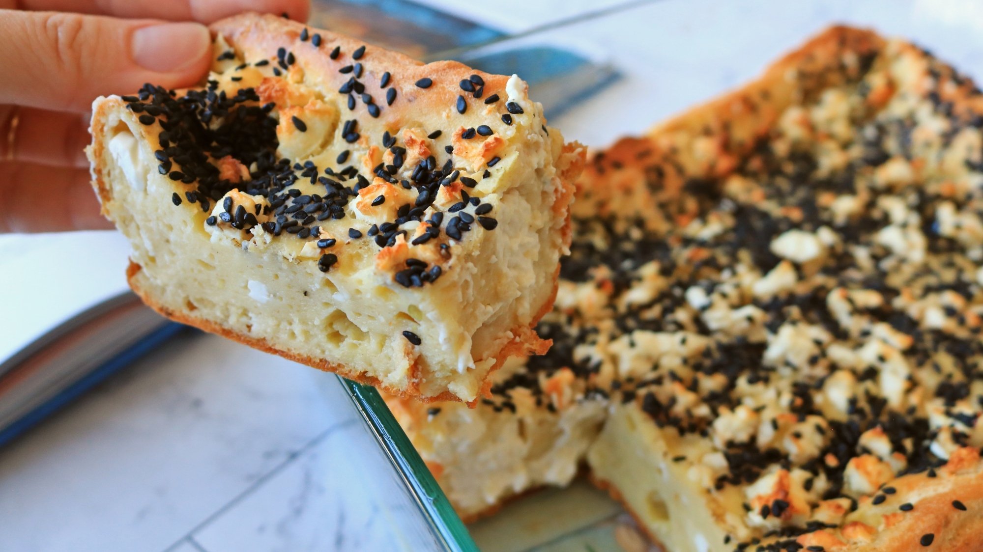 A hand holding a slice of Greek flatbread.