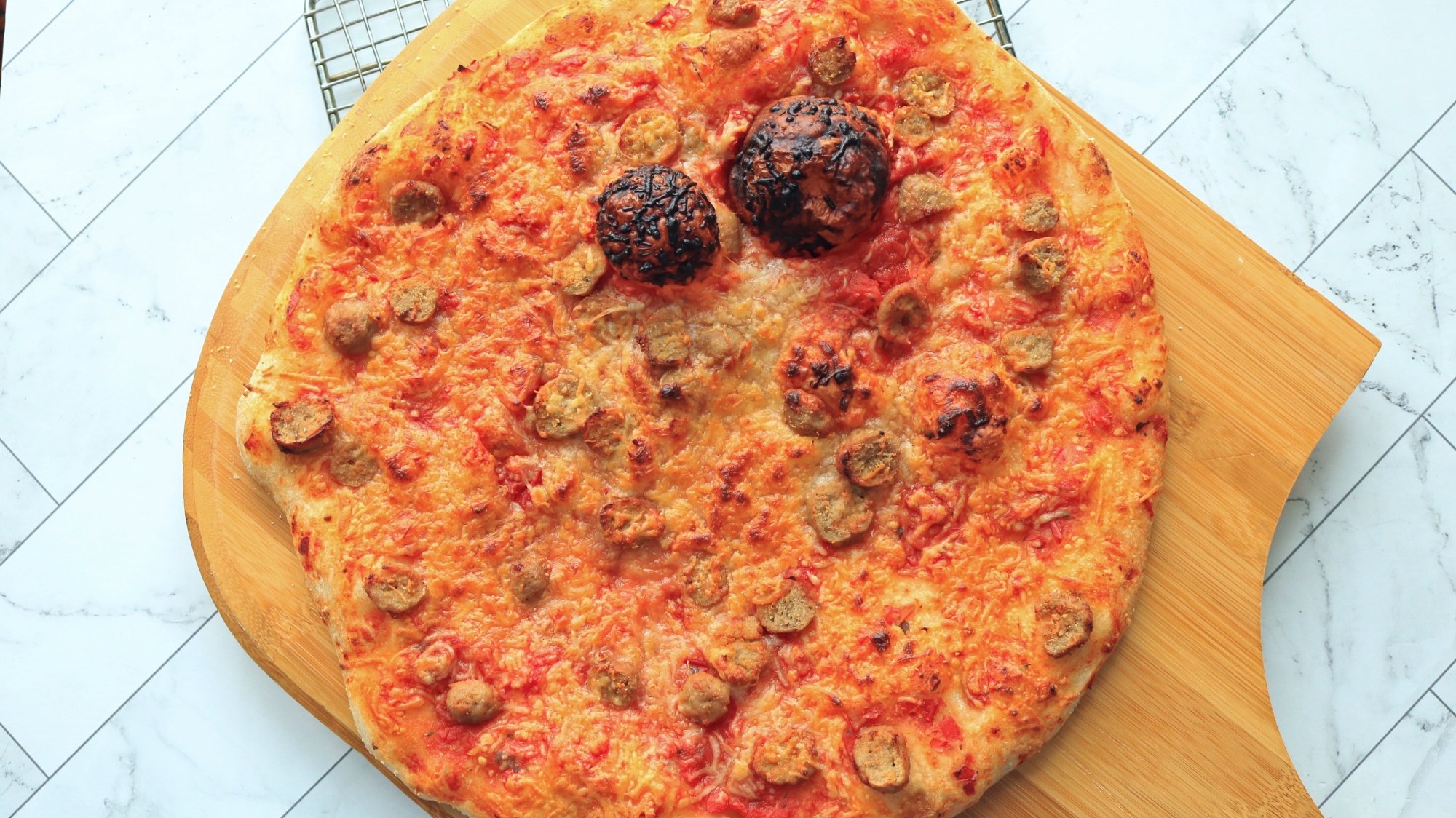 A pizza on a wooden pizza peel.