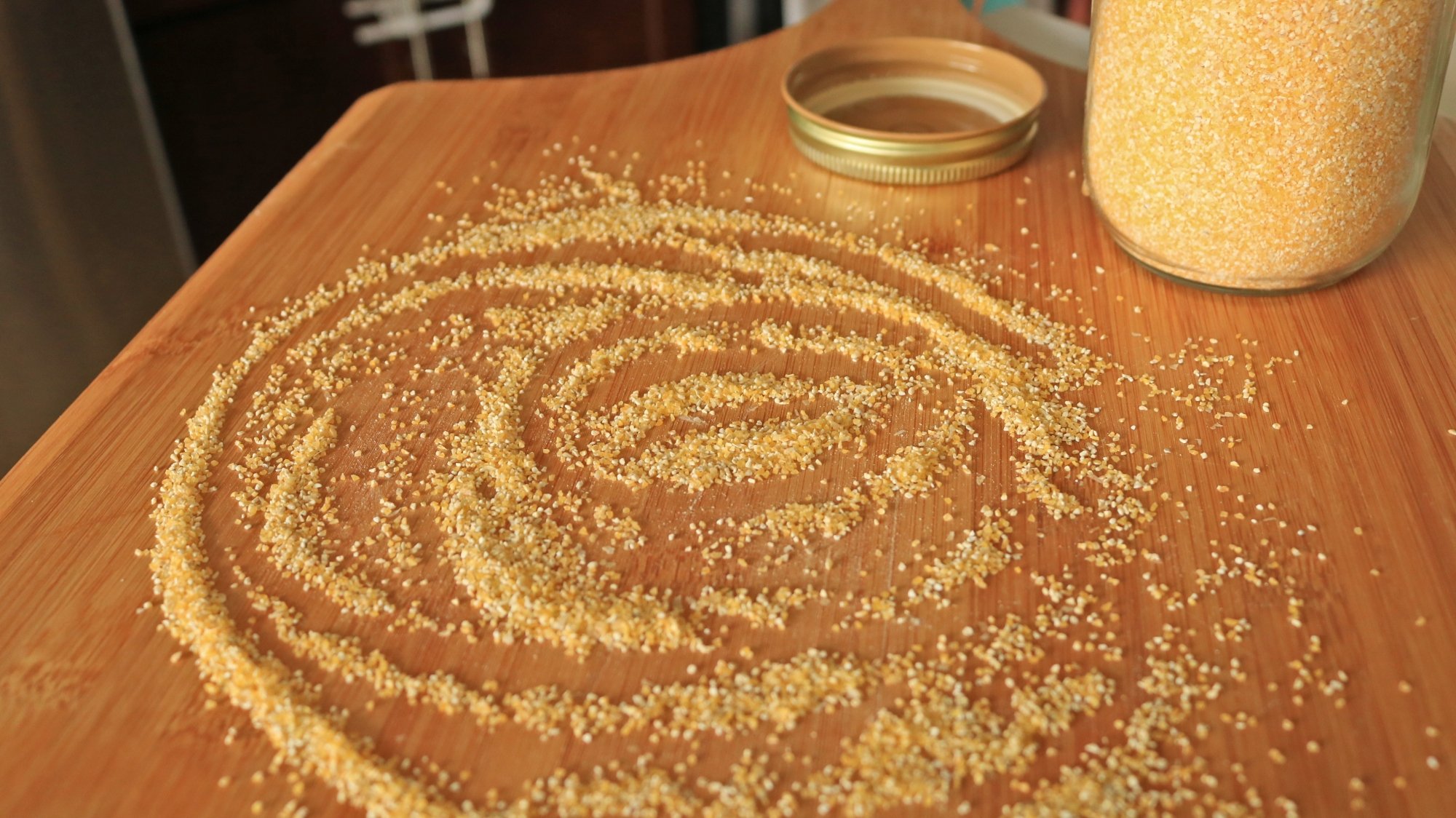 A wooden pizza peel with cornmeal on it.