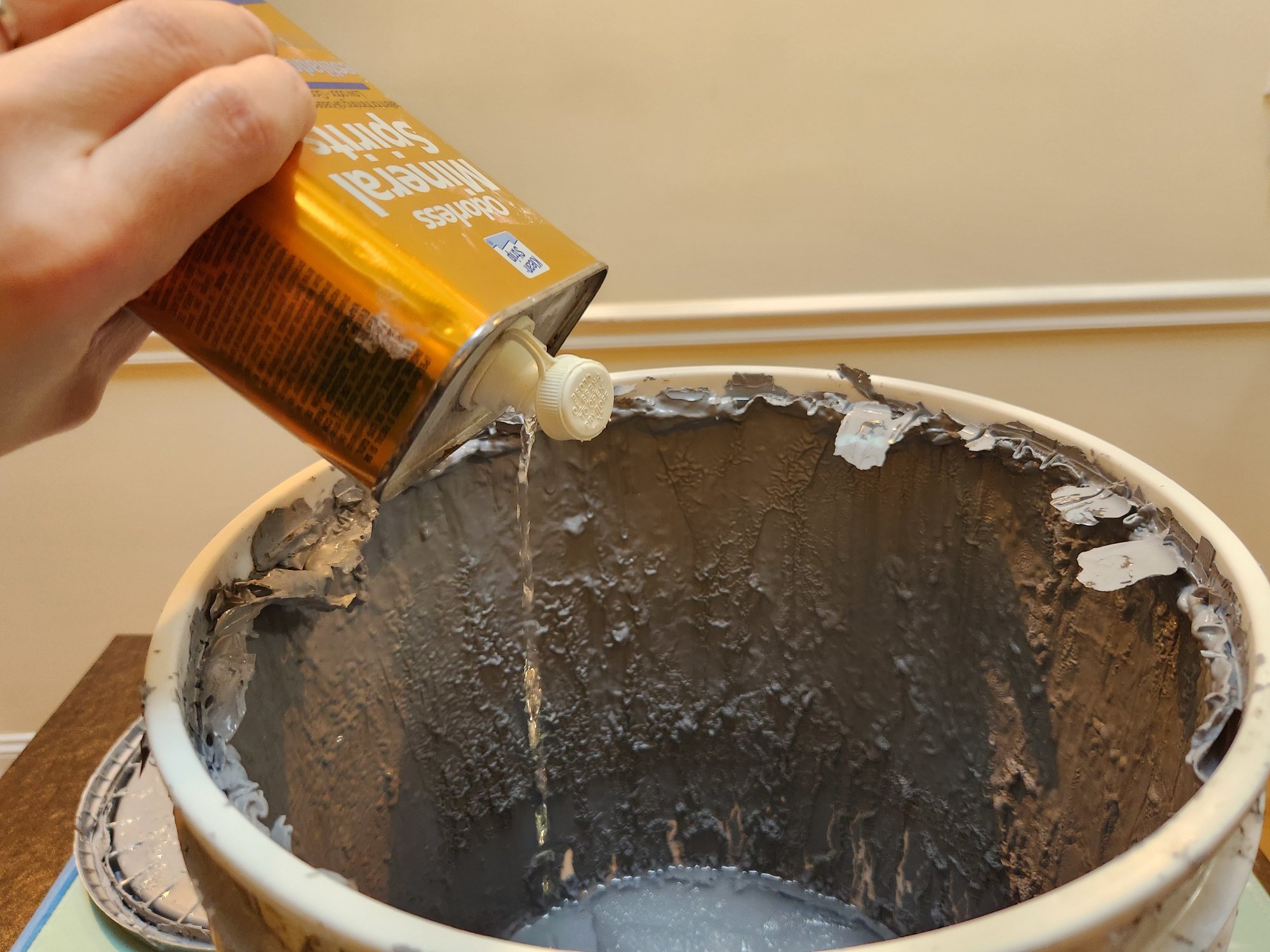 Pouring mineral spirits into old paint.
