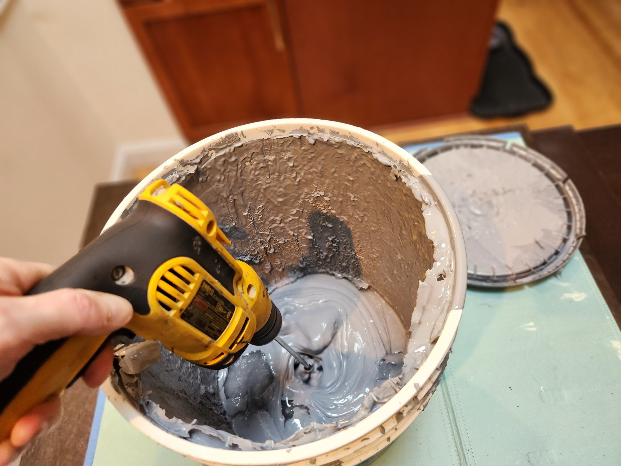 Mixing old paint with a power drill.