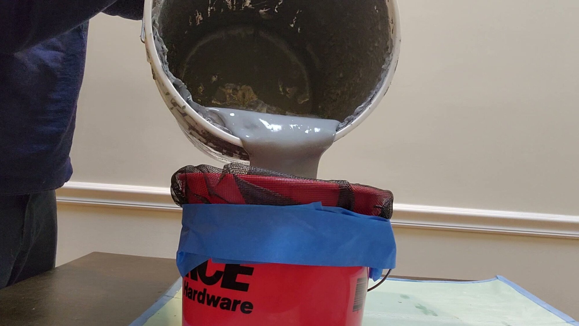 Pouring old paint into screened bucket.