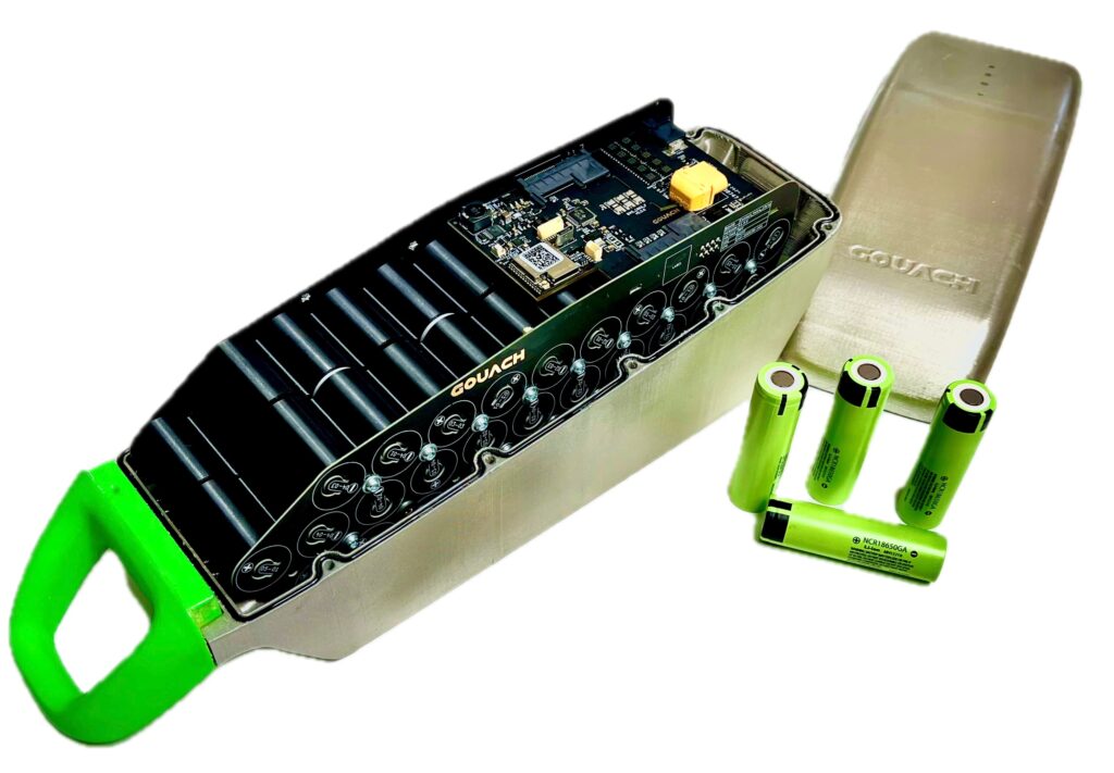 Gouach e-bike battery, with cells, circuit board connectors, and BMS exposed, with a few loose cells nearby.