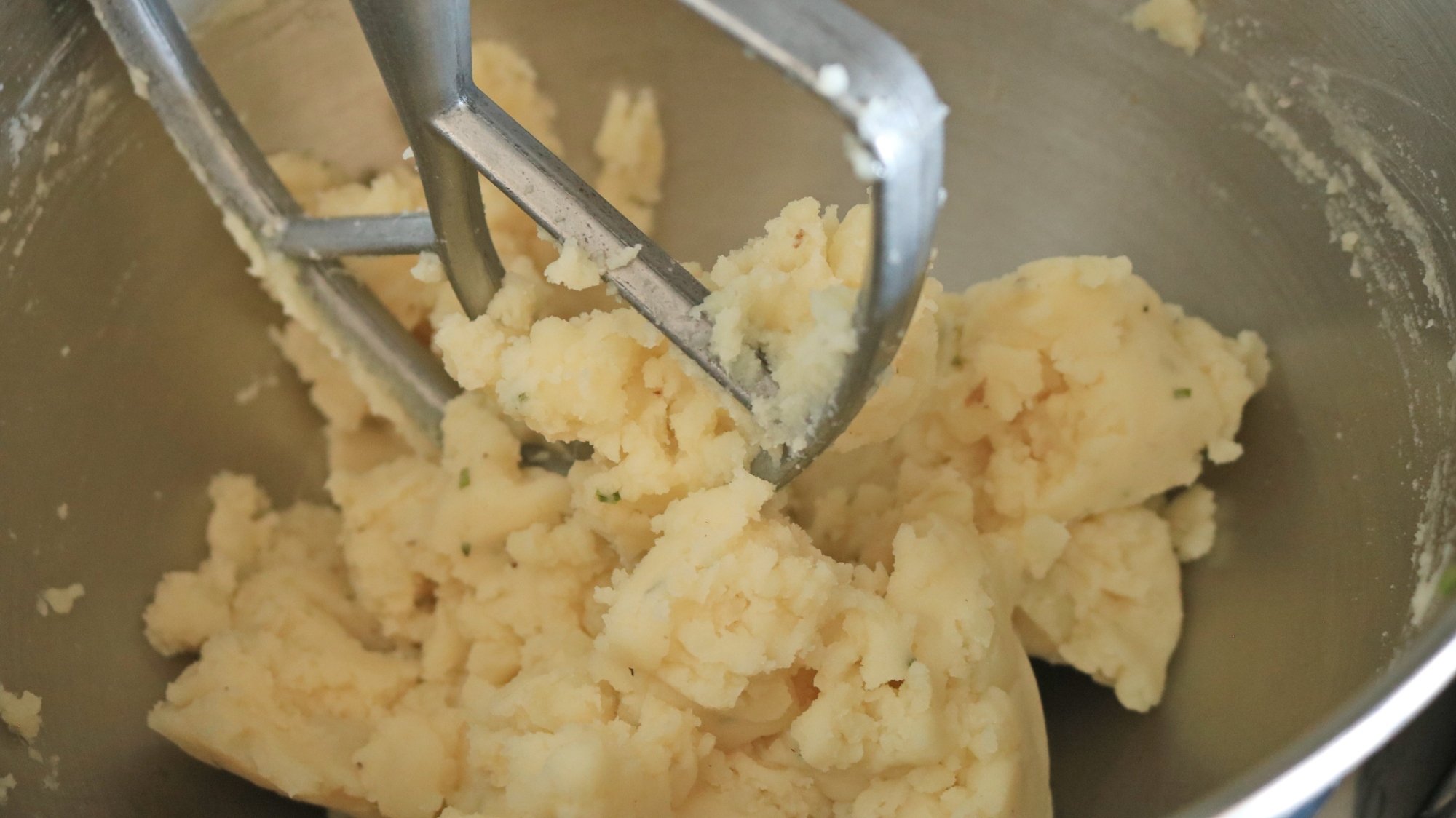 A stand mixer bowl with mashed potatoes inside.