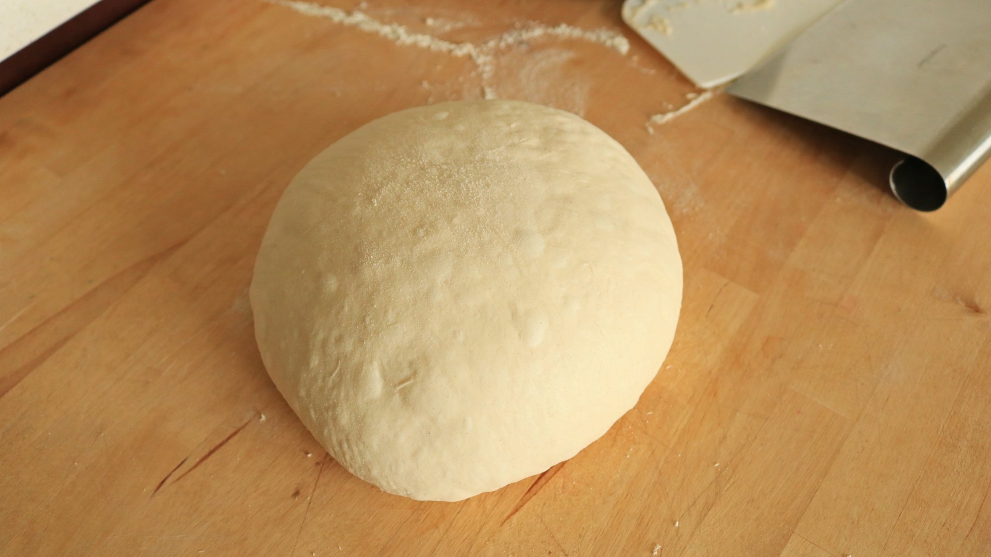 A ball of bread dough on a wooden counter.