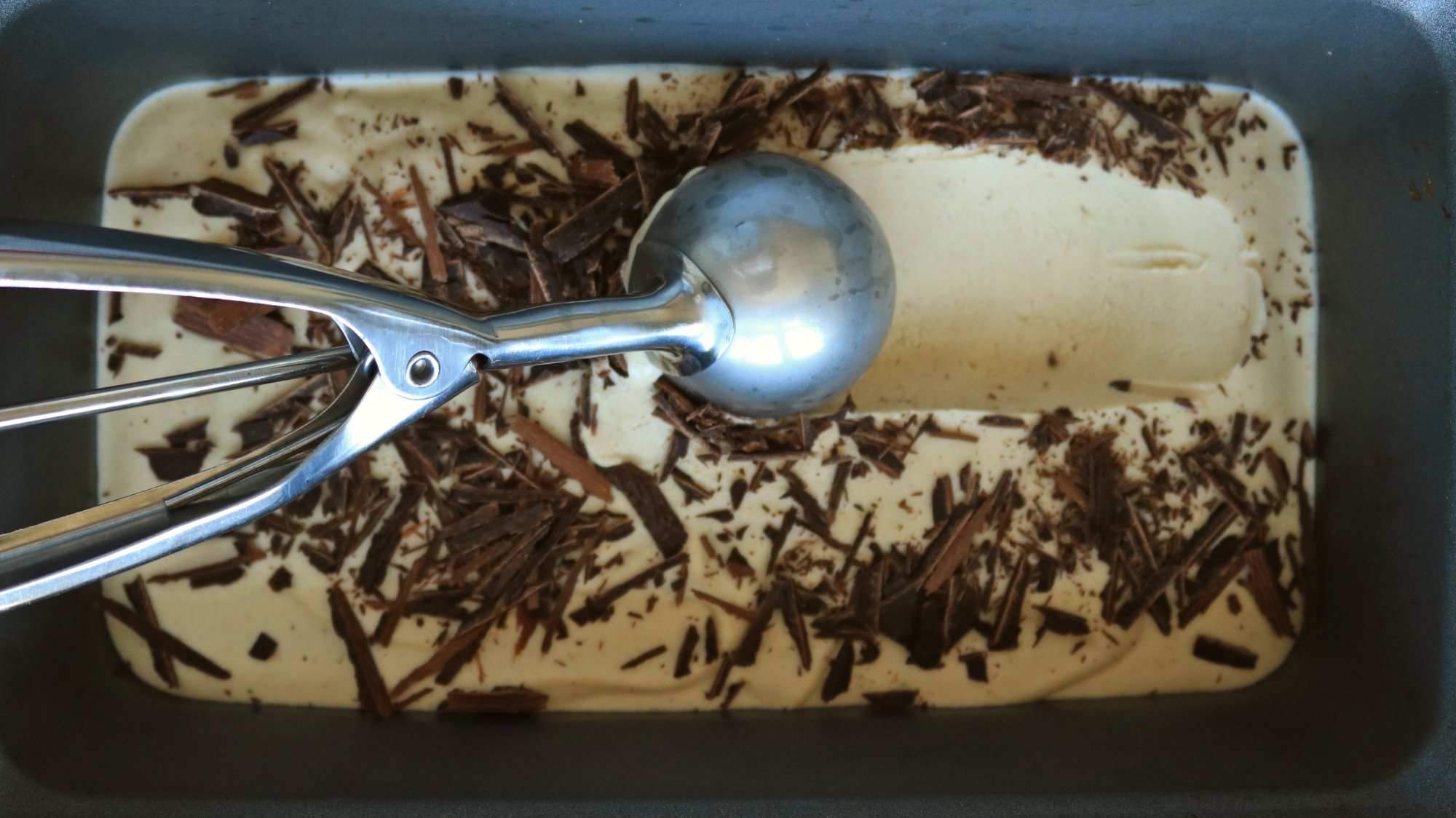 A metal ice cream scoop in ice cream.