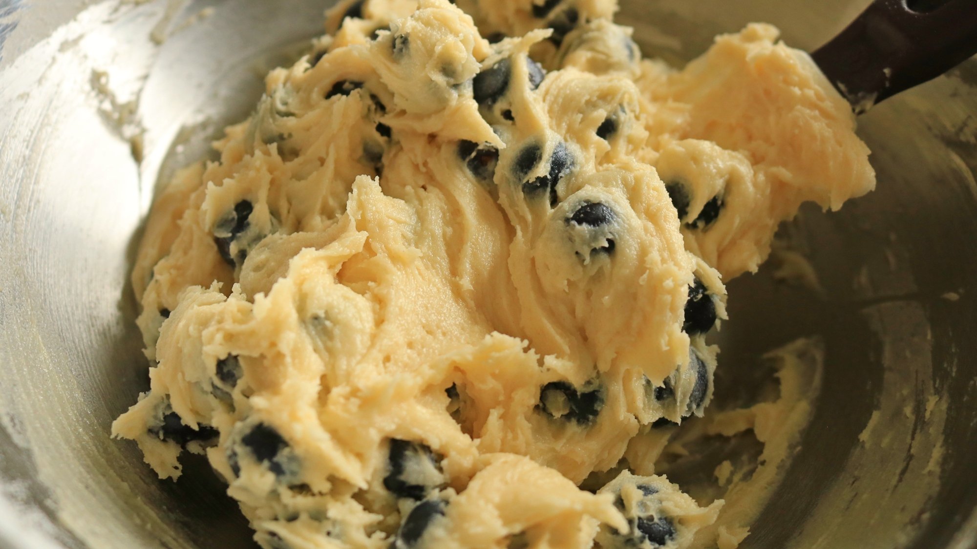 A bowl with blueberry cake batter inside.