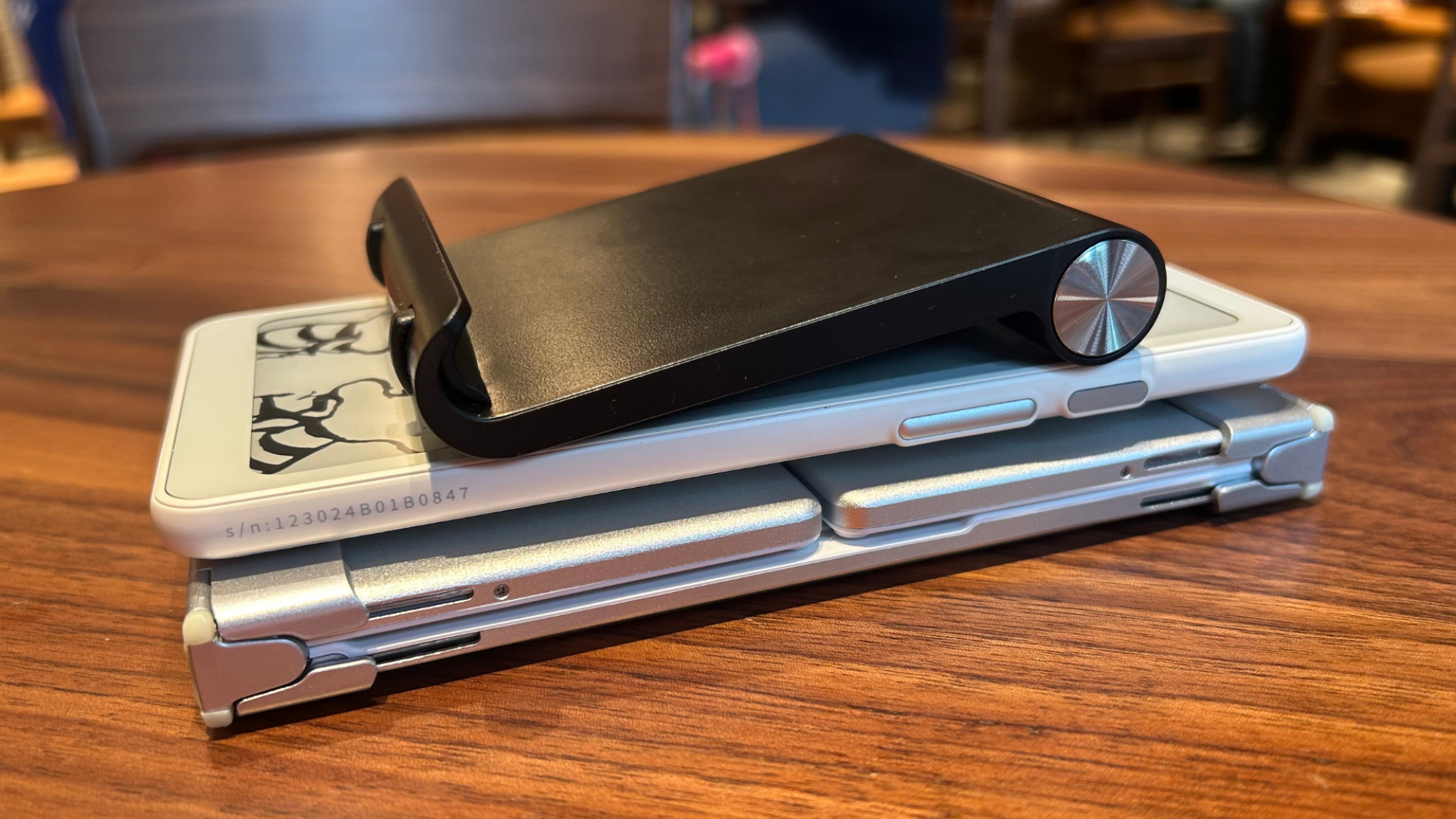 The Boox Palma, the iClever folding Bluetooth keyboard (folded up) and a small phone stand in a stack showing the similar thicknesses of each