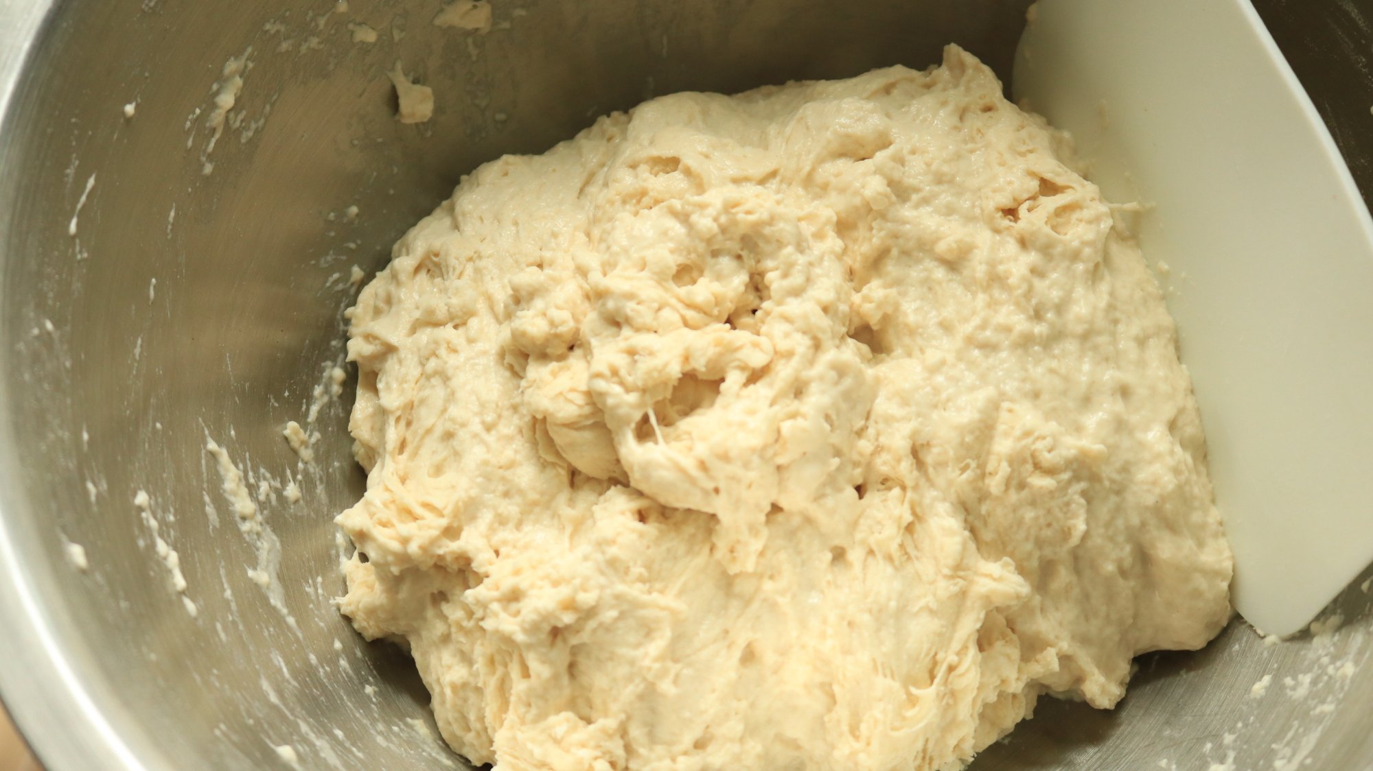 Bread dough in a silver bowl.