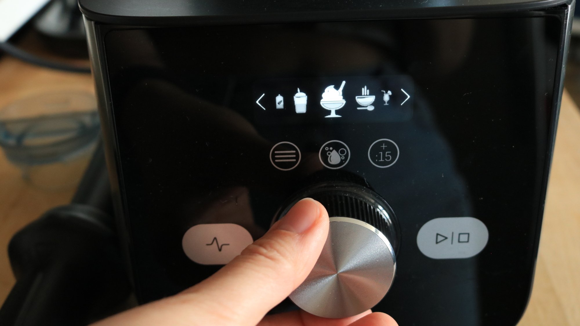 A person selecting a preset on the vitamix blender base.
