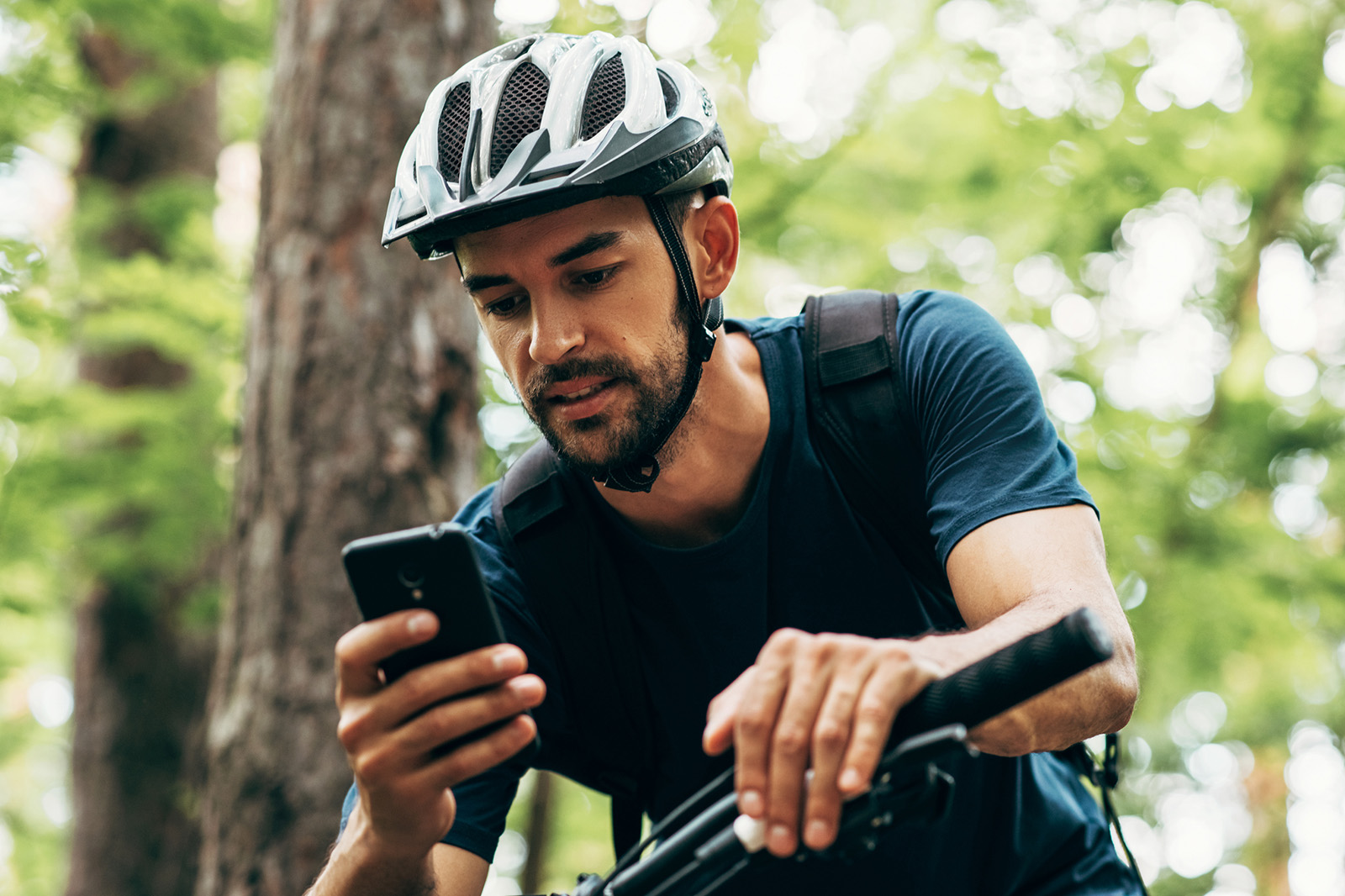 Man wearing bike helmet looking at phone.