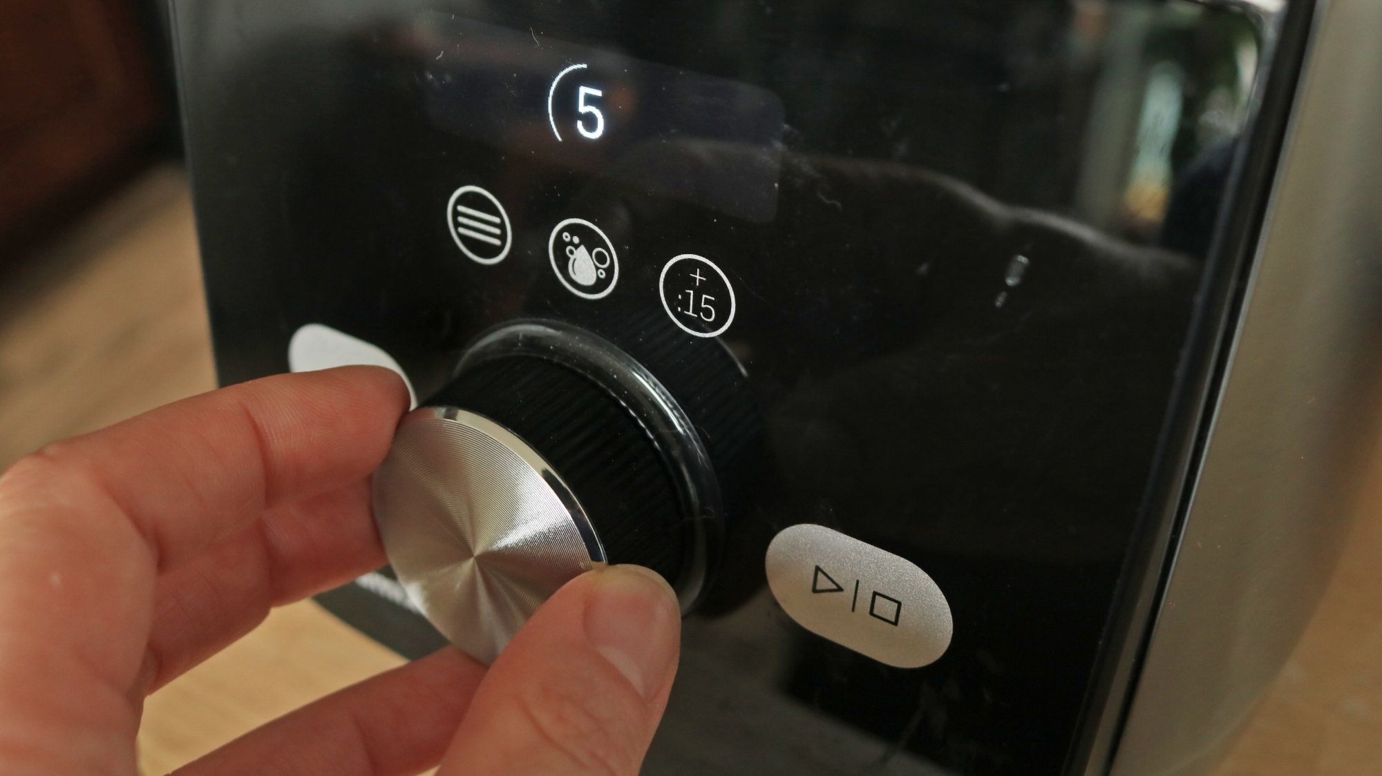 A person rotating the speed dial of a blender.