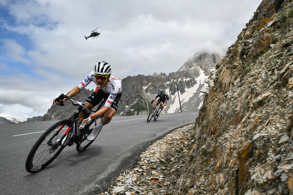 Two cyclist descending mountain with helicopter in background at Tour de France.