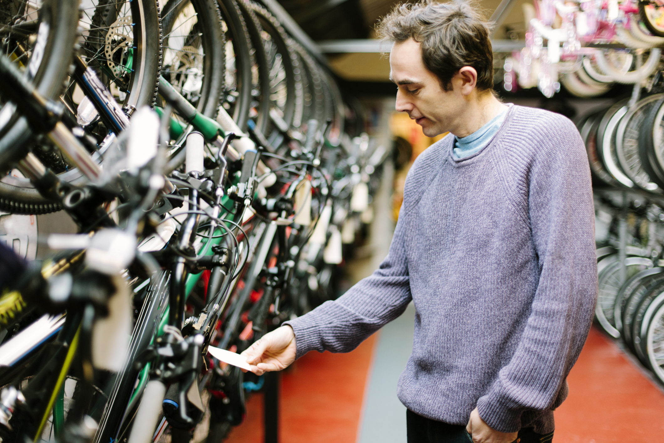 Customer in a bicycle shop, smiling and looking at the price label.