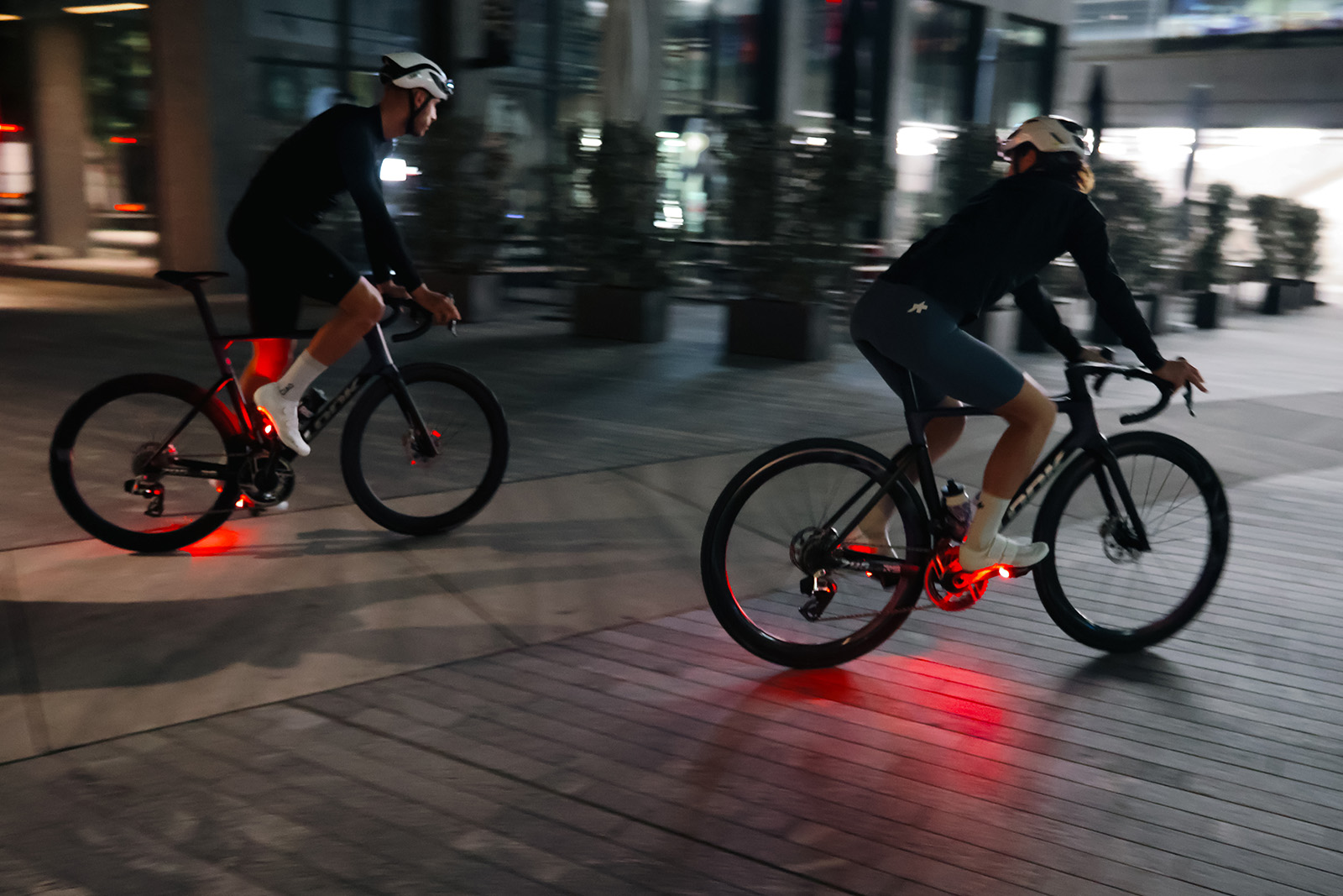 Two people riding bikes at night with Look Keo Vision bike light pedals.