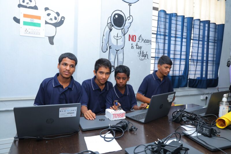 Four students at laptops in a school in India.