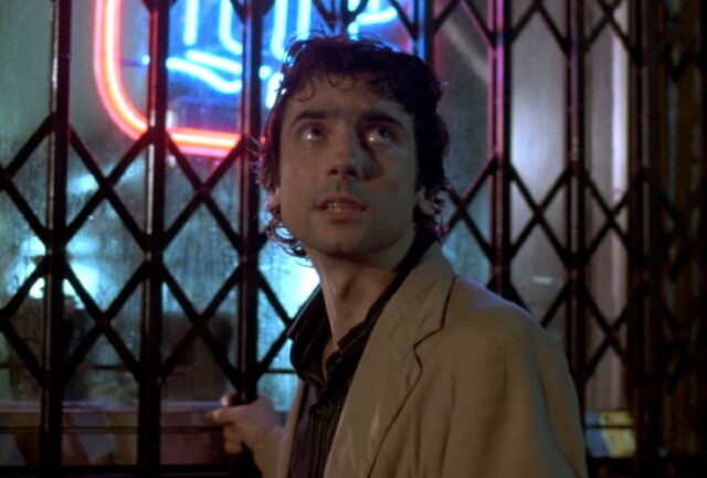 young nerdy man in black shirt and casual tan jacket looking anxious