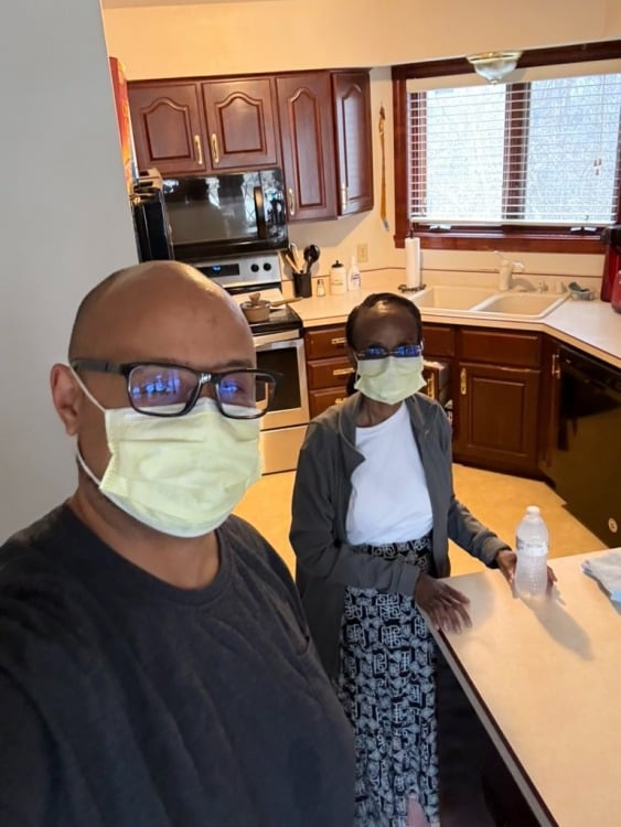 man and woman wearing medical masks in a kitchen