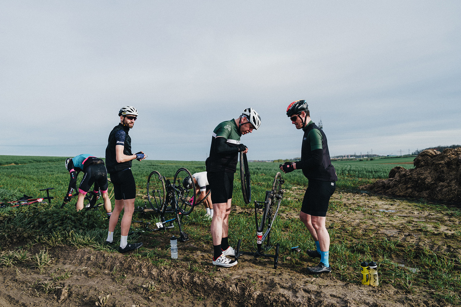Group of cyclists during the Paris-Roubaix Challenge repairing punctures