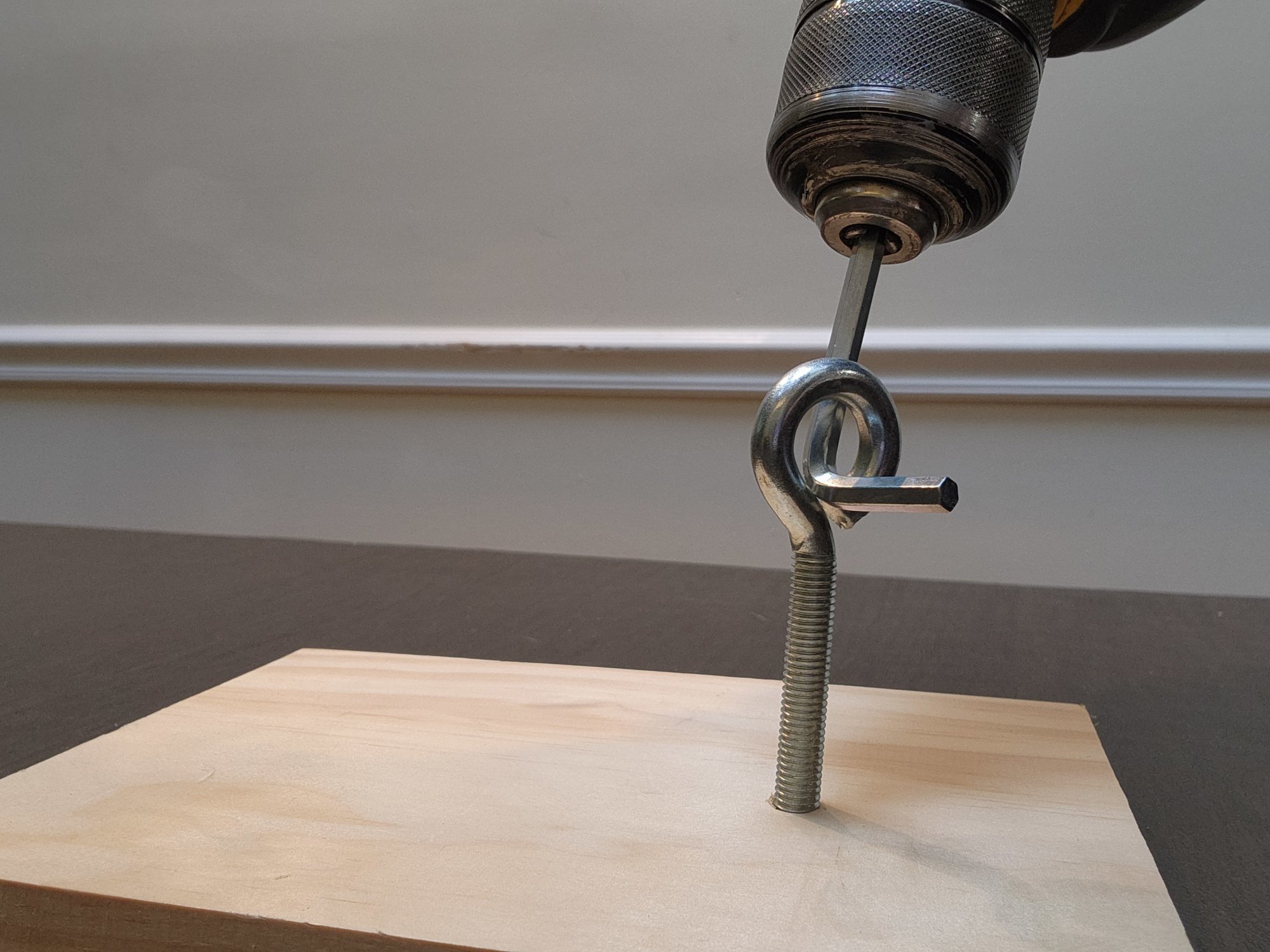 Power drill and Allen wrench being used to extract eyehook