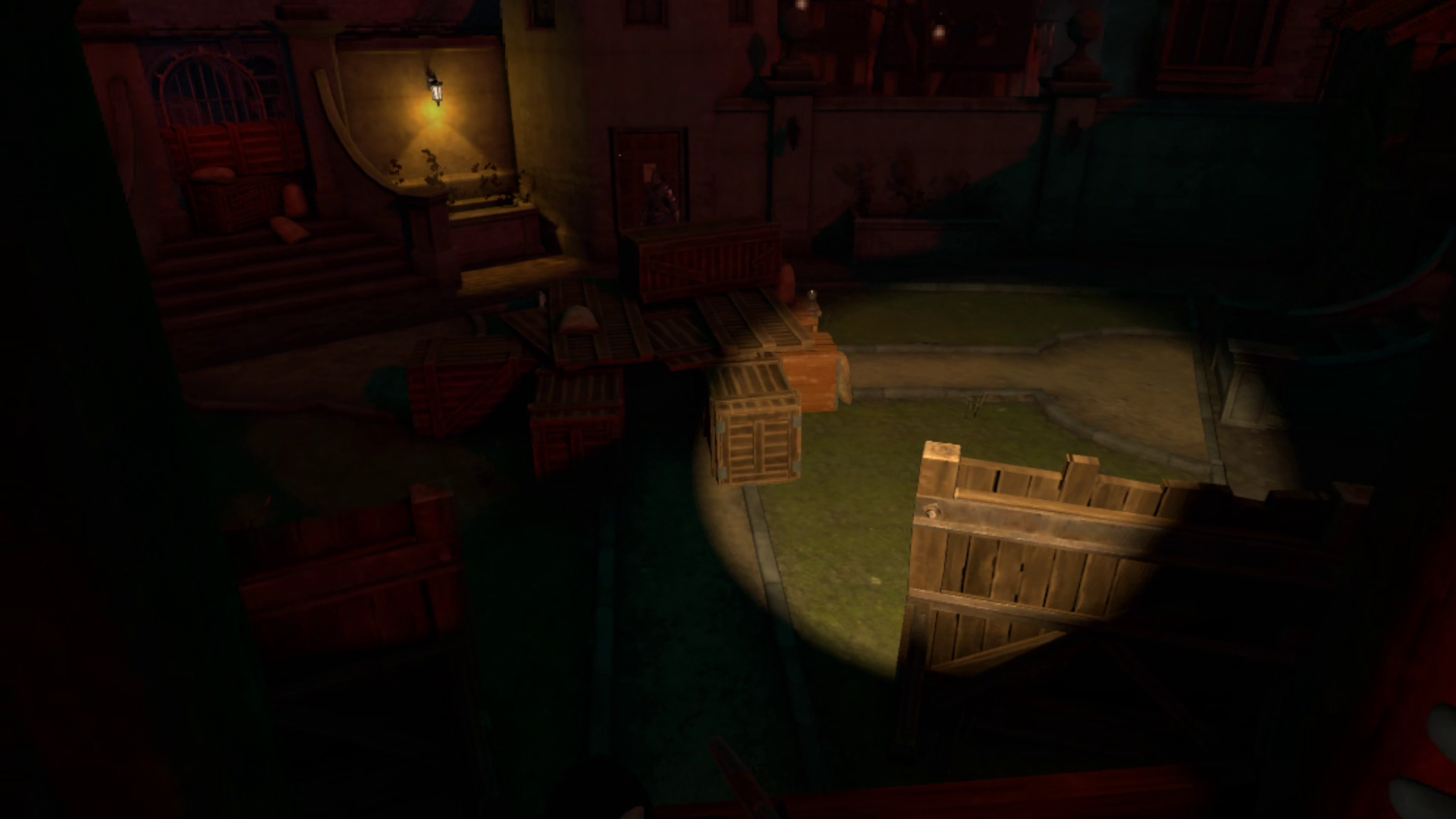 A crate-filled courtyard is cast in a red hue night glow, save for a yellow spotlight off to the right, and a lantern on a wall to the left. A guard is at his post in a tower opposite the player's POV.