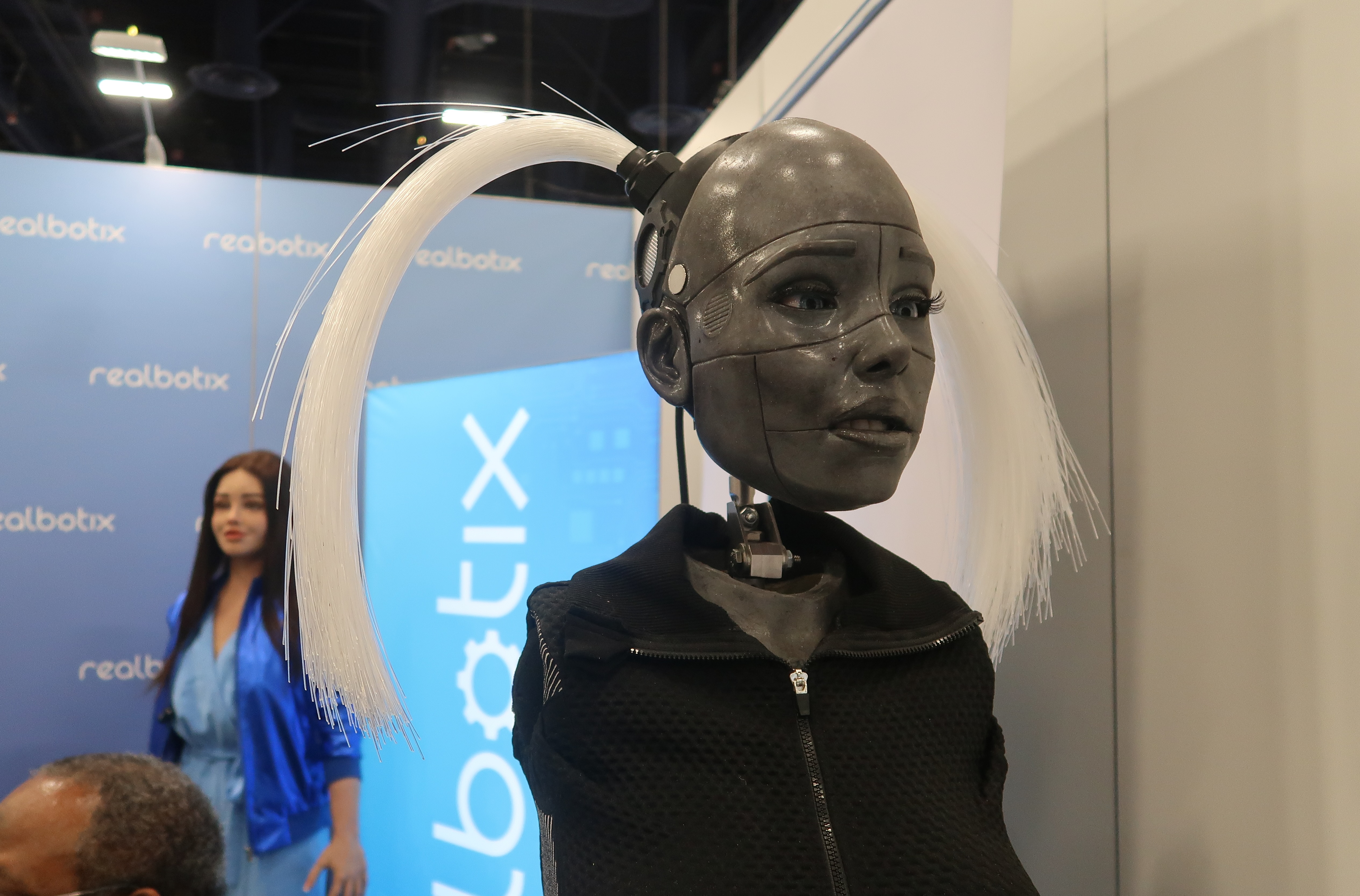 One of Realbotix robots pictured from the chest up. She is a dark gray color, and has white pigtails