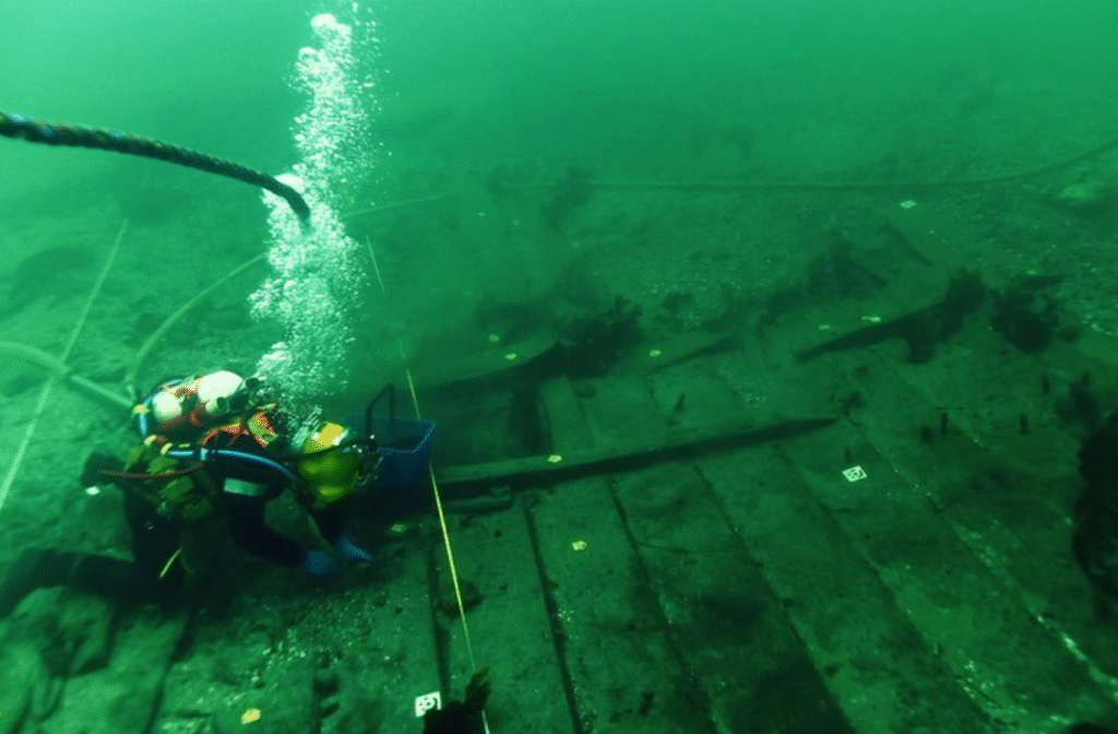 photo of a scuba diver swimming over wooden planks underwater