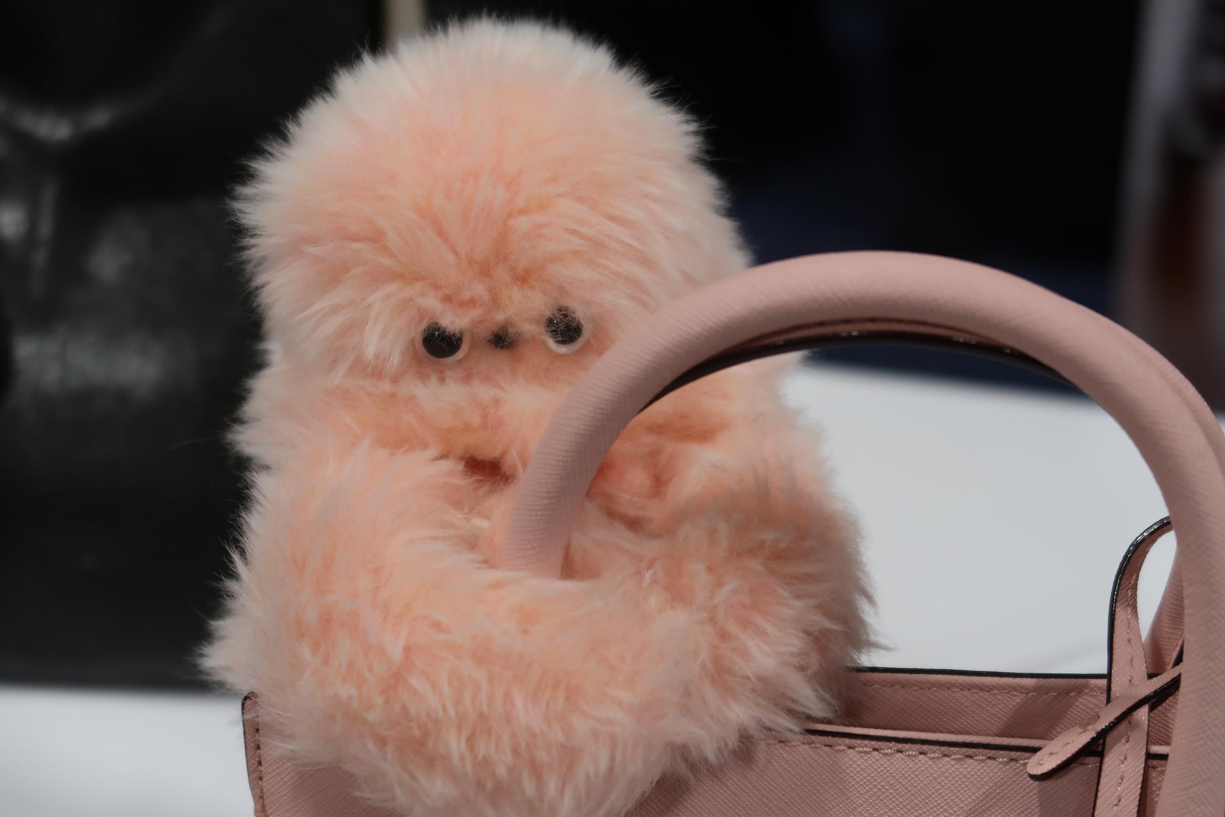 A Mirumi robot sticks to a pink purse. 