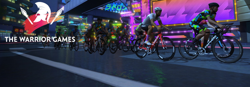A group of cyclists race through a brightly lit, futuristic city at night with neon signs. The logo and text “The Warrior Games” appear on the left side of the image.
