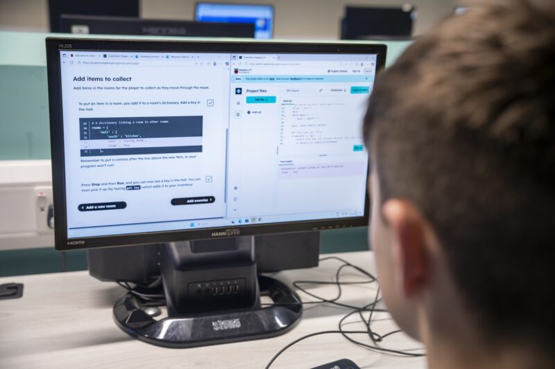 A young learner uses the Code Club Projects site on computer to do Python coding.
