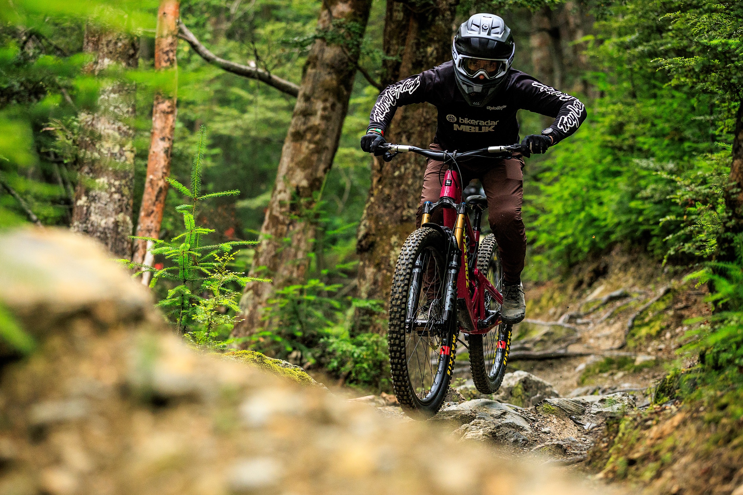Rider descending a rocky trail wearing a full face helmet and using the new SRAM Maven brakes.