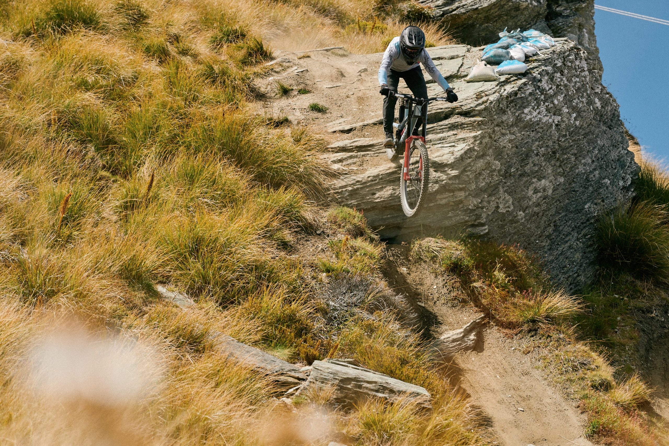 Rider dropping off exposed rock on Coronet Peak DH course, riding the new RockShox Boxxer fork.