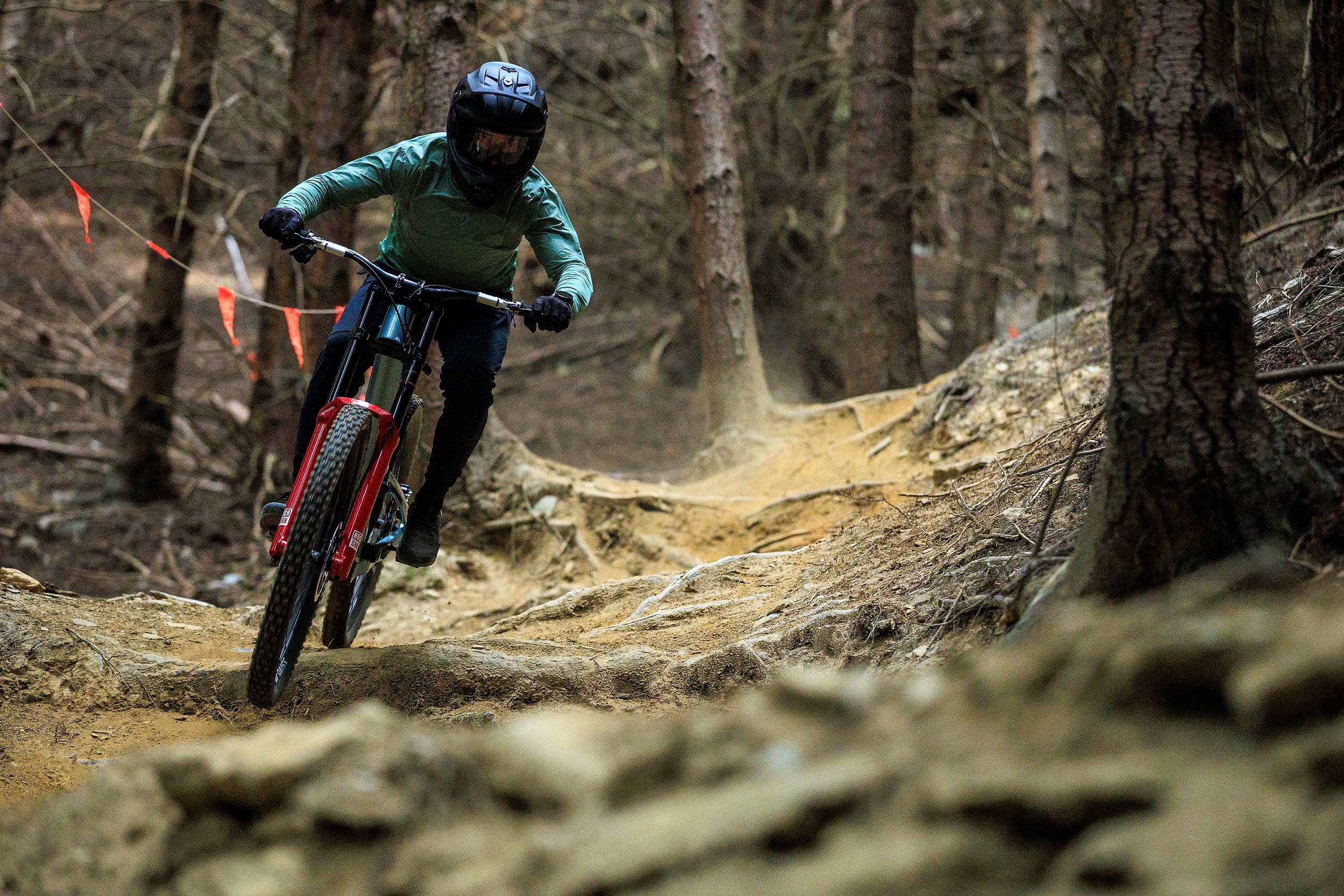Rider on downhill bike and in full face helmets riding down a rocky and rooty downhill track in Queenstown bike bike, New Zealand.