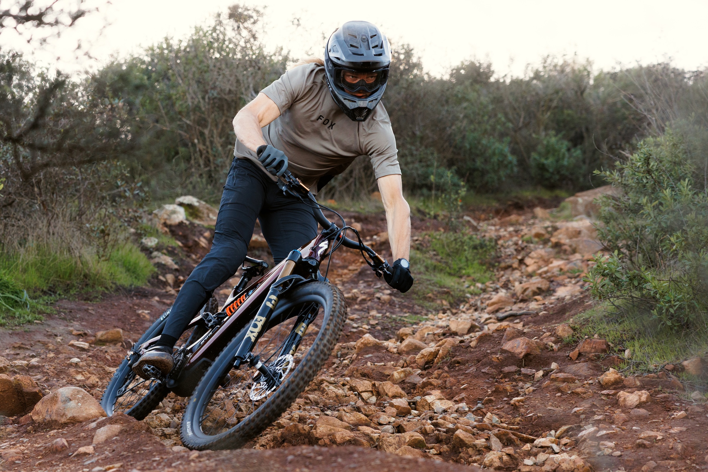 Mountain biker cornering aggressively on loose terrain using Fox 38 suspension fork