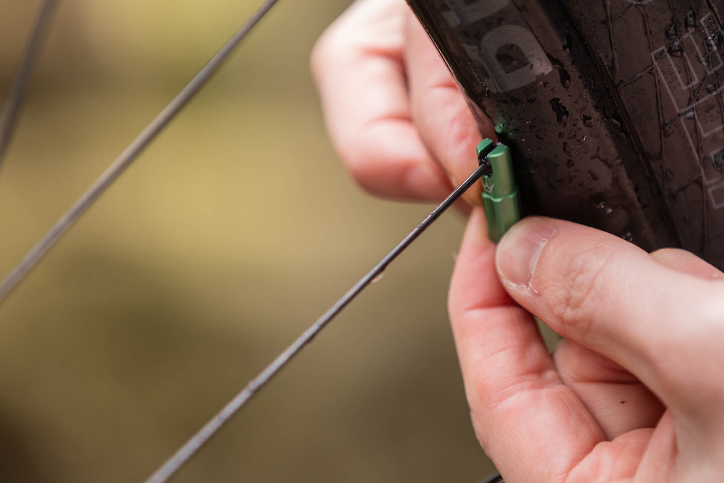 Peaty's Holeshot Fast Flow spoke key valve cap being used to turn a spoke nipple.