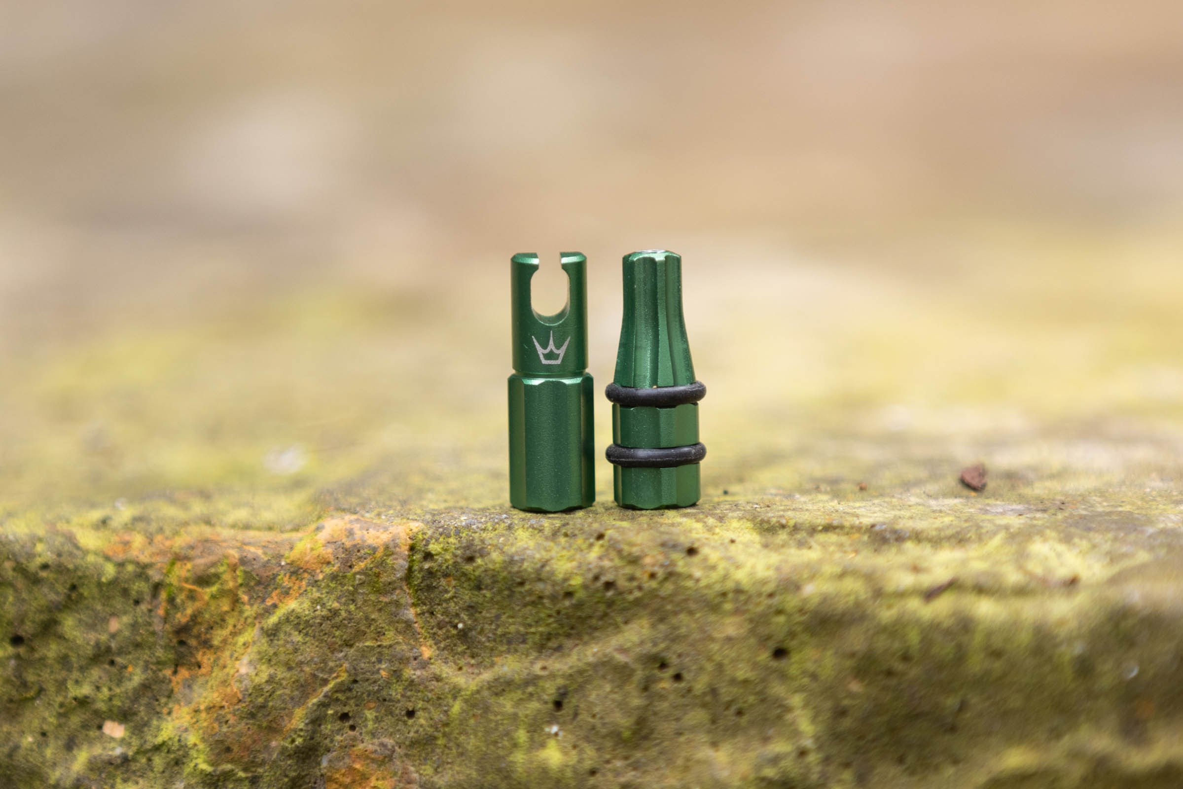 Peaty's Holeshot Fast Flow valve caps stood upright on a stone surface.